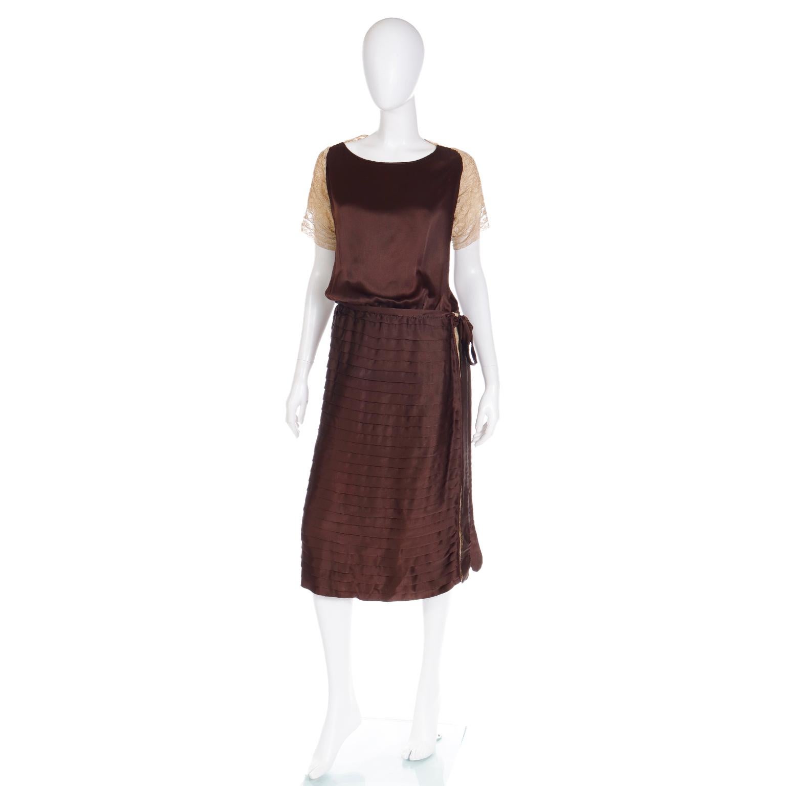This beautifully made vintage 1920s dress is in a dark chocolate brown silk with cream lace on the sleeves and upper back. We love the way the dress has horizontal flat pleats along the entire skirt portion and a side seam with insert lace. There is