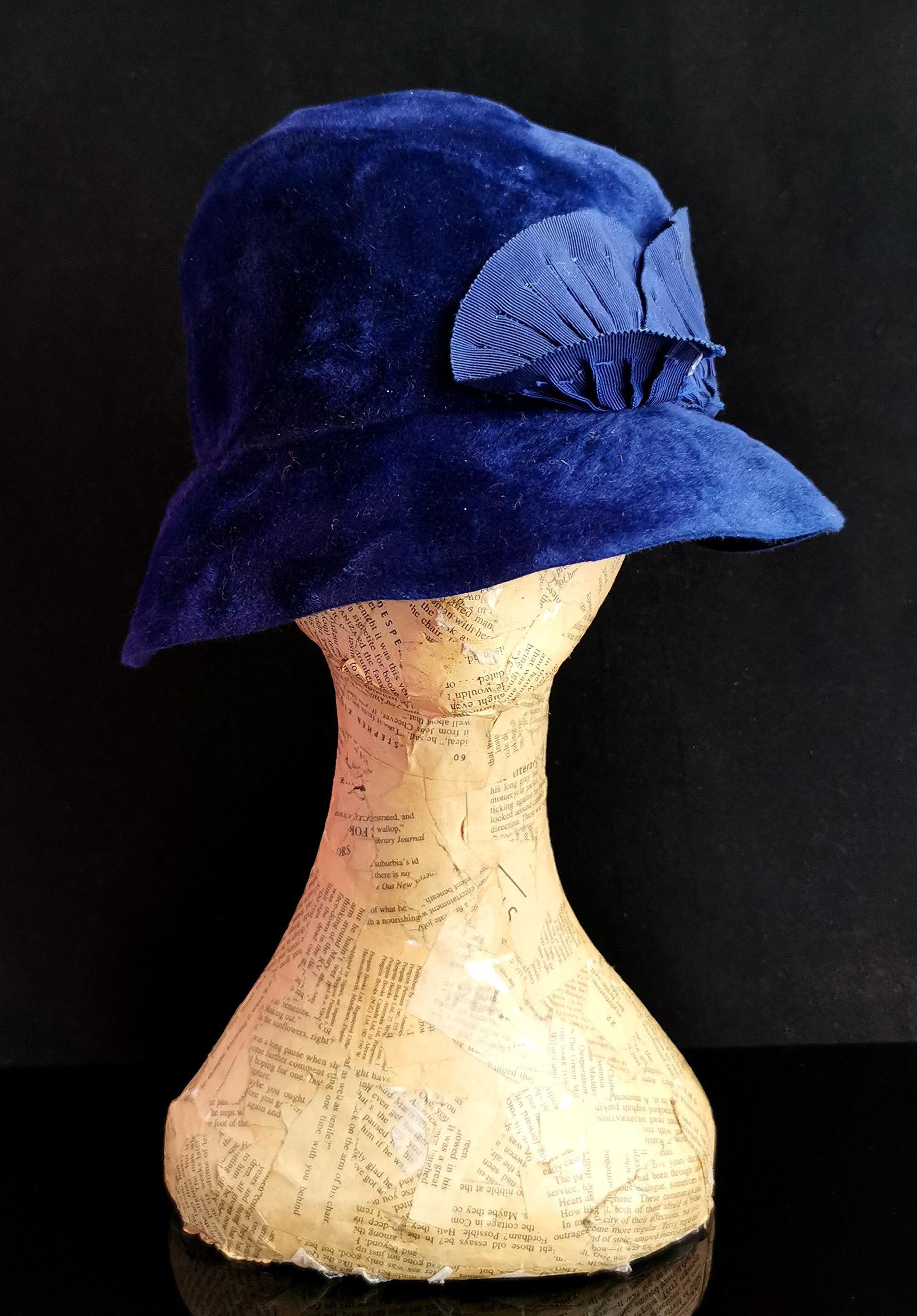 A beautiful vintage late 1920s era cloche hat.

A deep bucket style cloche hat with a short floppy brim in a rich cobalt blue.

The hat has a woven half band with fanned detailing and this spans around one half of the hat.

It has a fairly long and