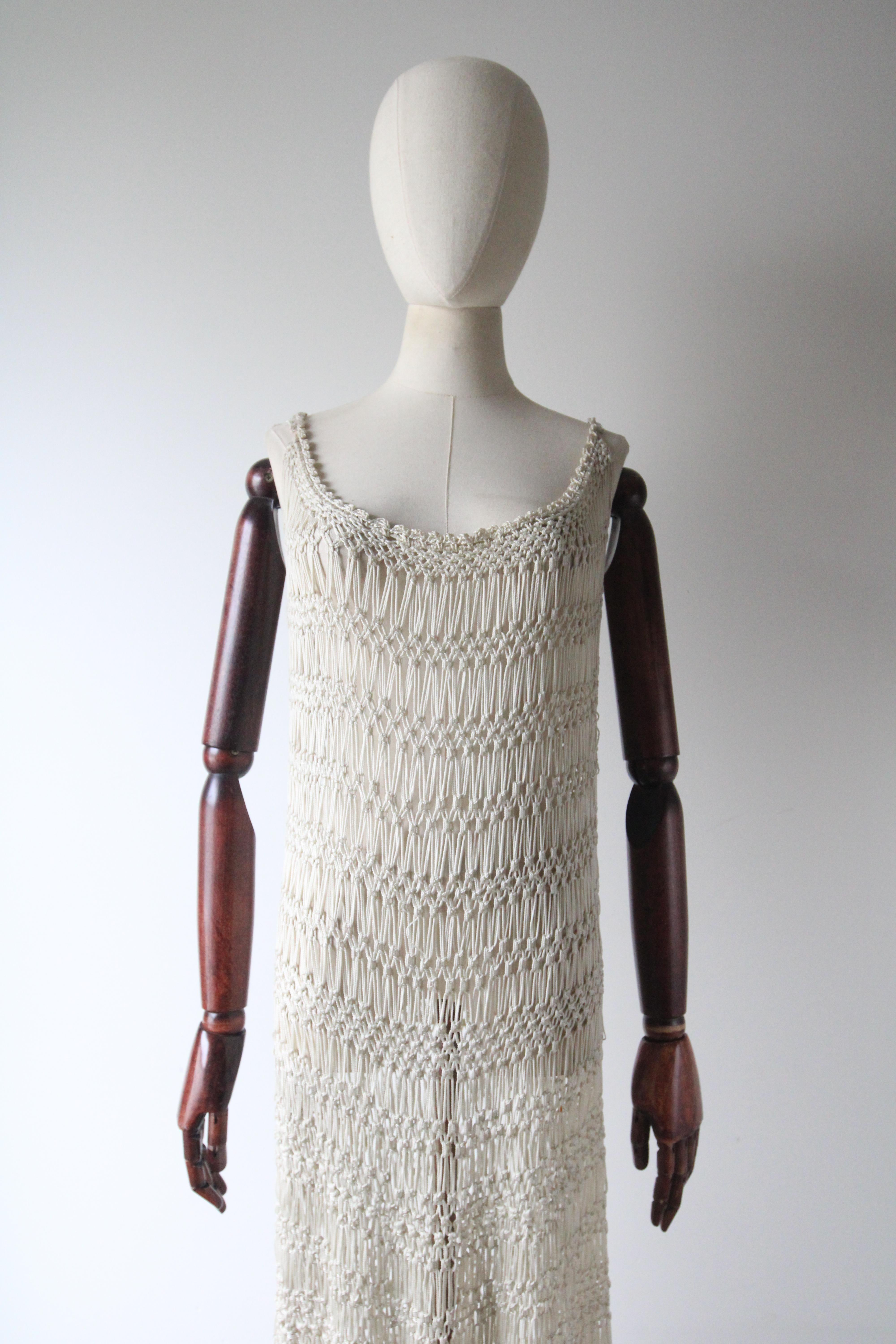 Rendered in the most mesmerising knotted and crocheted design, this original 1920's cream dress, is the perfect statement piece to add to your vintage collection. 

The rounded neckline is framed by a detailed crochet scalloped edge, threaded along