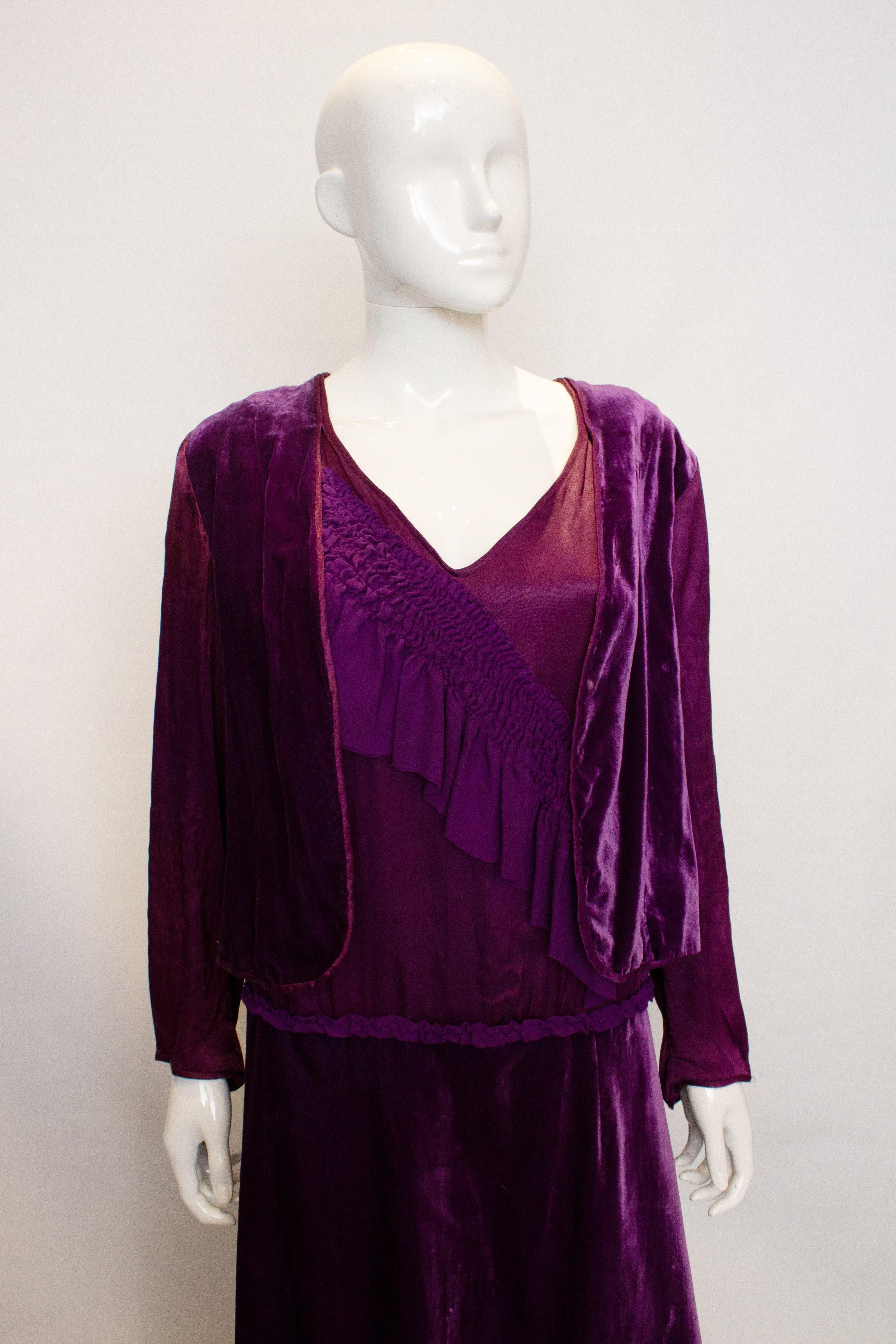 Ein atemberaubendes violettes Kleid aus den 1920er Jahren. Das Kleid hat einen V-Ausschnitt und eine Seidenraffung auf der Vorderseite. Es hat Ärmel aus Satin und Rüschen am Rücken. 
