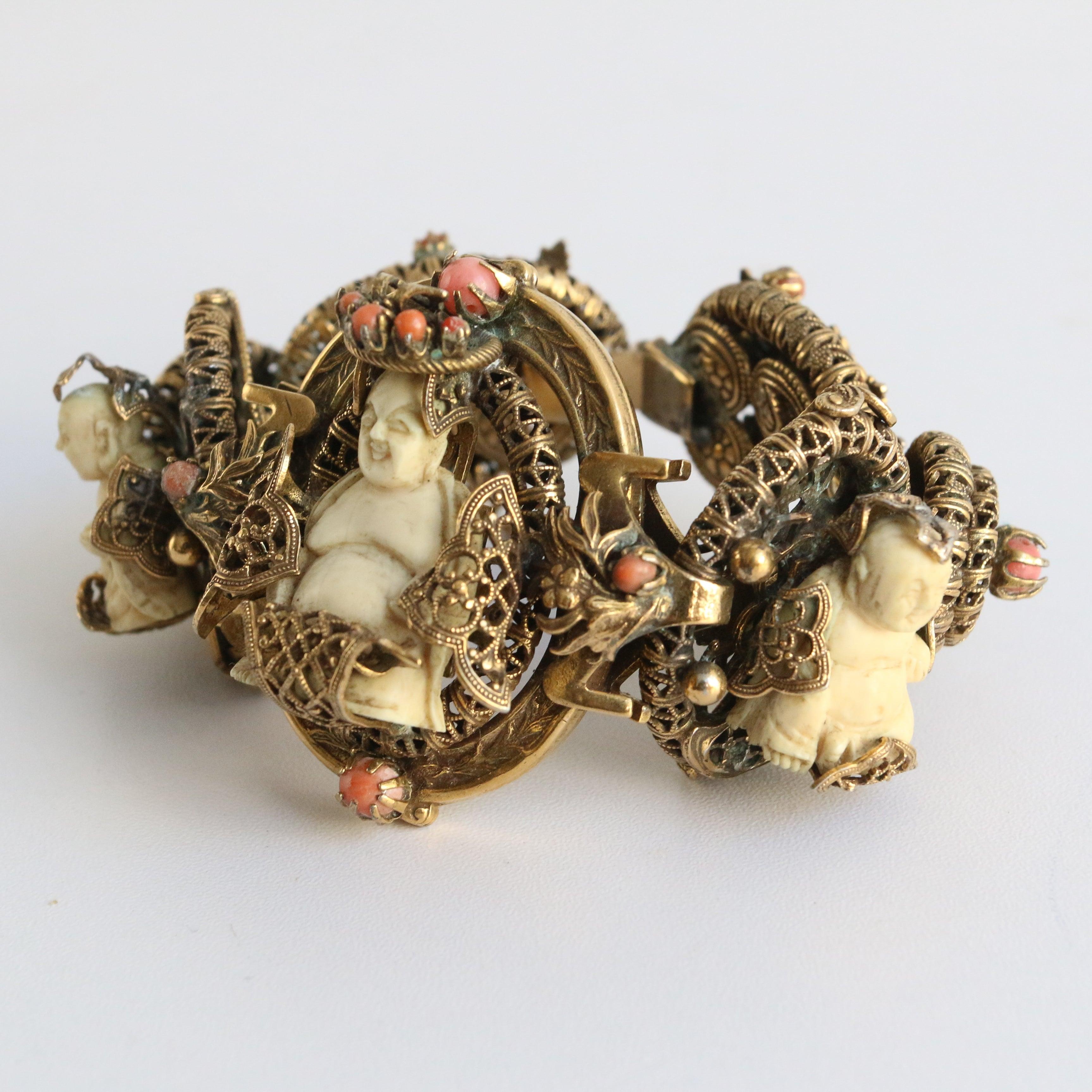 Ce bracelet en laiton filigrané des années 1920, orné de coraux en peau d'ange sertis et de bouddhas bovins sculptés, dans un cadre Trikaya, est une pièce rare. Les cinq bases reliées entre elles sont ornées de motifs et de dessins en filigrane et