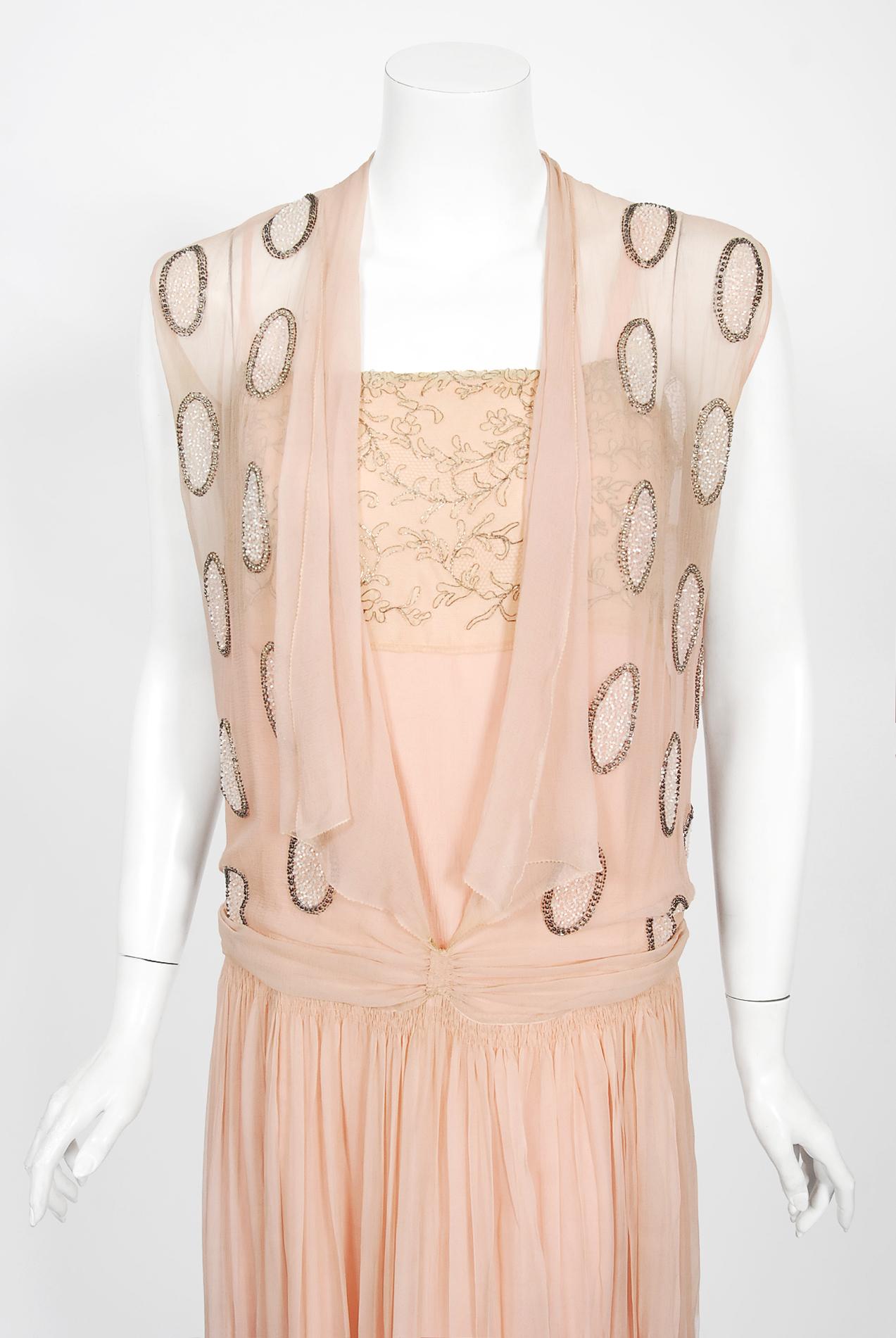 Undiminished by time, this 1920's ballerina slipper pink beaded flapper dance dress still casts its magical spell. This exceptional French beauty is fashioned in silk chiffon with lavish pink, ivory and metallic silver beading. I adore the bold deco