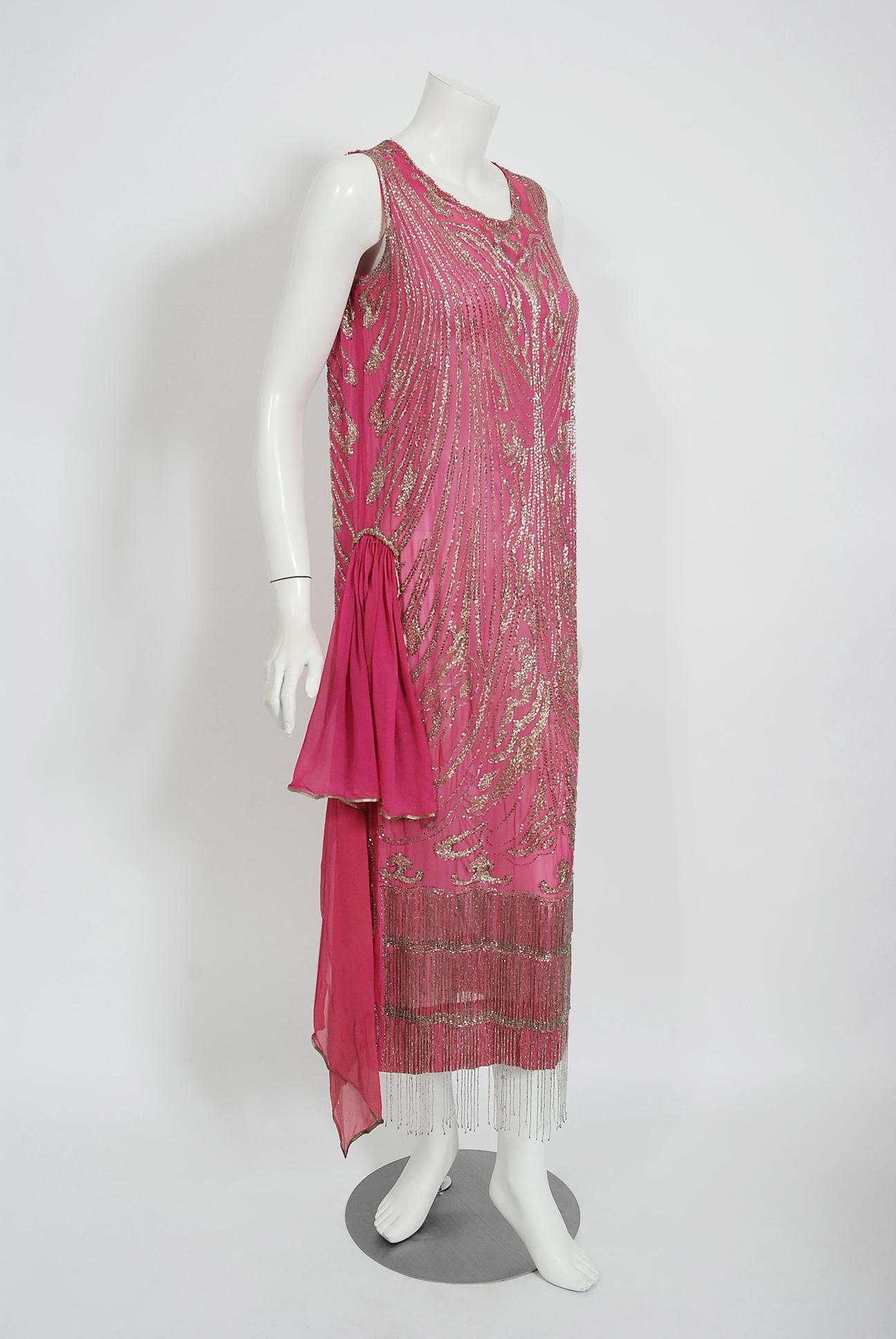 Undiminished by time, this 1920's fuchsia-pink flapper dance dress still casts its magical spell. This exceptional French beauty is fashioned in silk chiffon with lavish metallic silver embroidery and beading. I adore the bold art-deco motif worked