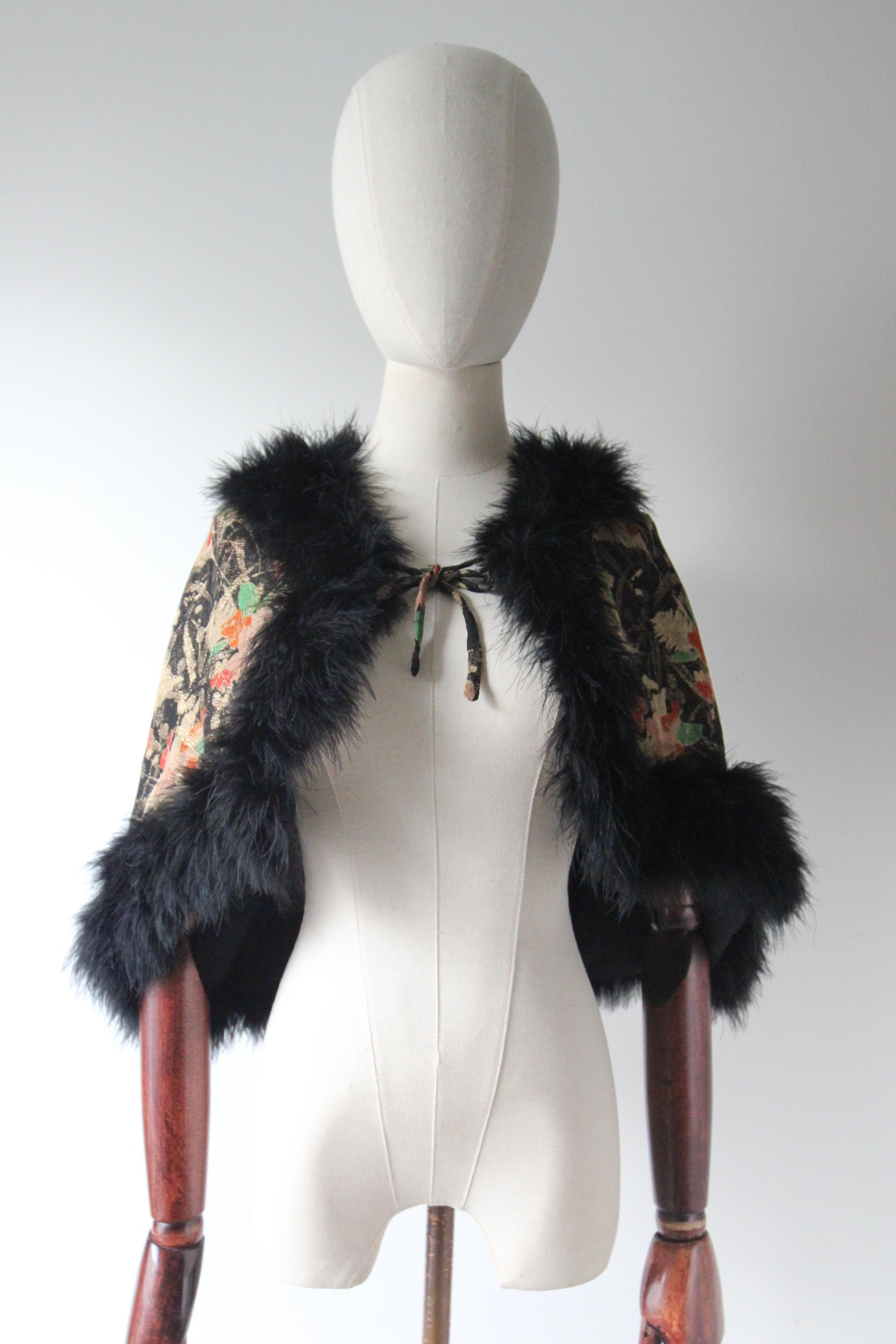 A rare piece to behold this original 1920's silk floral lamé cape, edged with the softest black marabou trim, is just the perfect statement piece for your cocktail wardrobe. 

The elegant V shaped neckline of the cape is framed by a marabou edge