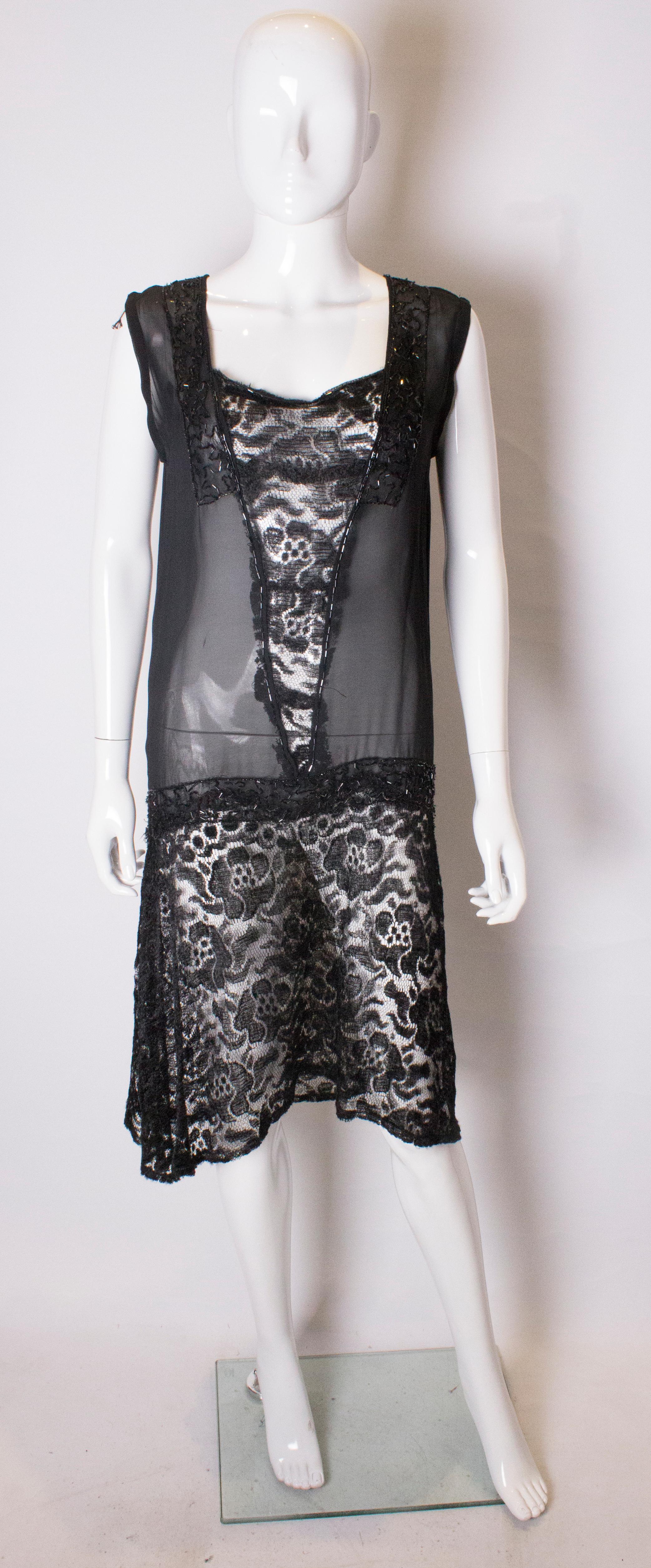 A pretty 1920s style cocktail dress. The dress has a v neckline with a lace skirt  , central lace panel and bead decoration.