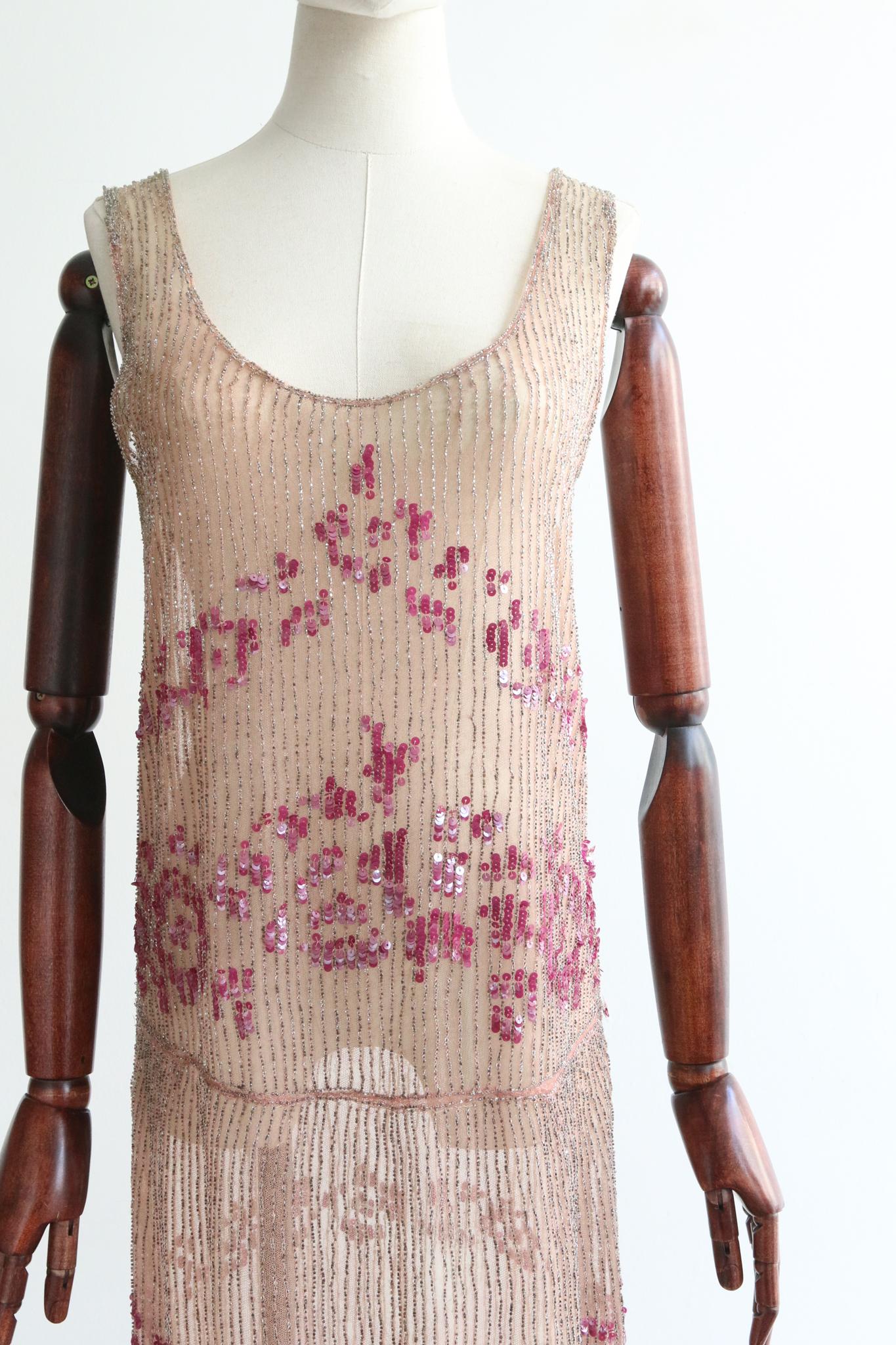 Full of opulent original details, rendered in the most luxurious fashion, this rare 1920's piece is a beauty to behold. 

Her rounded neckline is framed by wide shoulder straps and matching rounded backline. The straight cut bodice of the dress sets