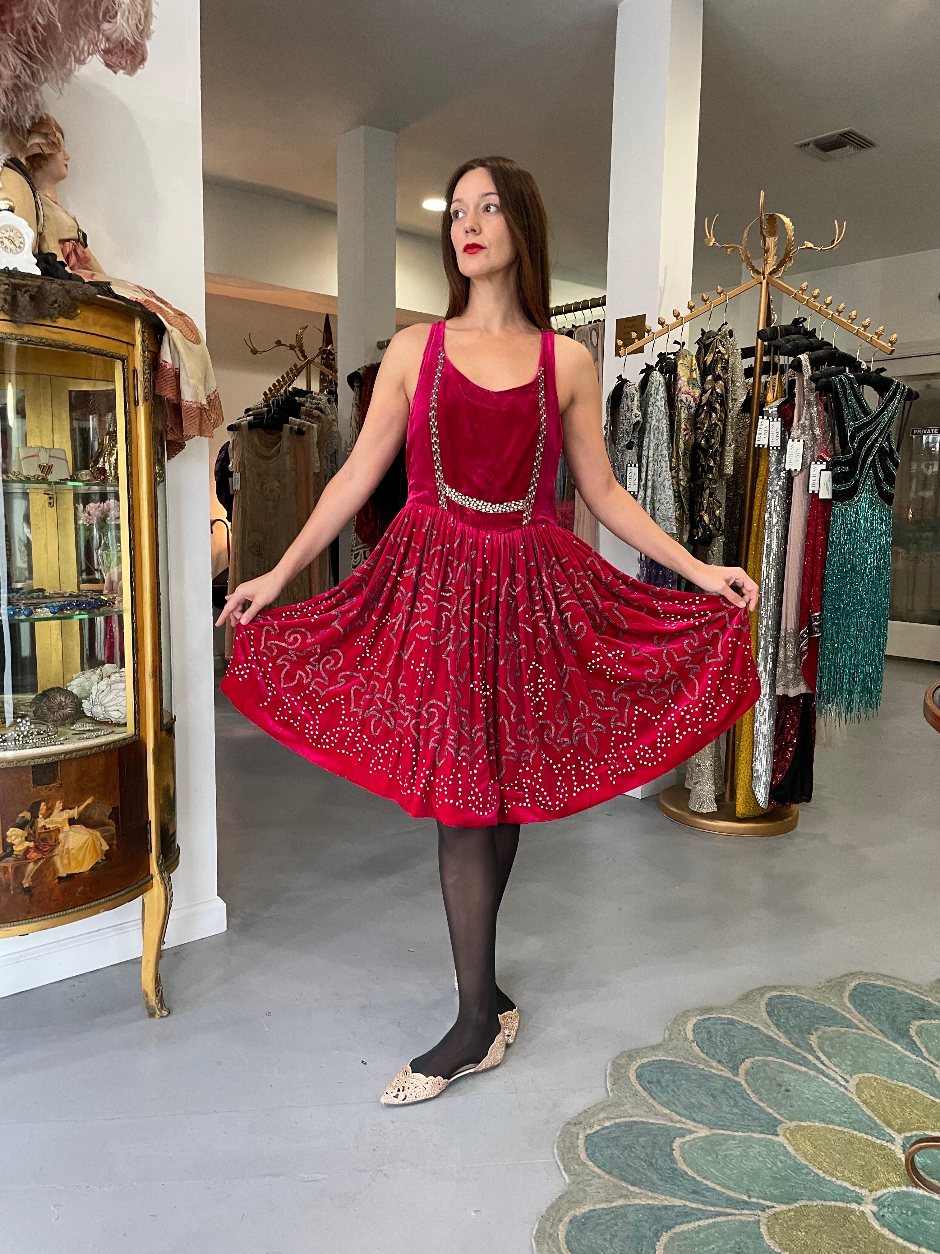A simply stunning and seldom found magenta pink heavily beaded silk-velvet dance dress dating back to the mid-1920's. Vibrant colored flapper dresses from this decade are perennial favorites and this one is a show-stopper. The garment's simple