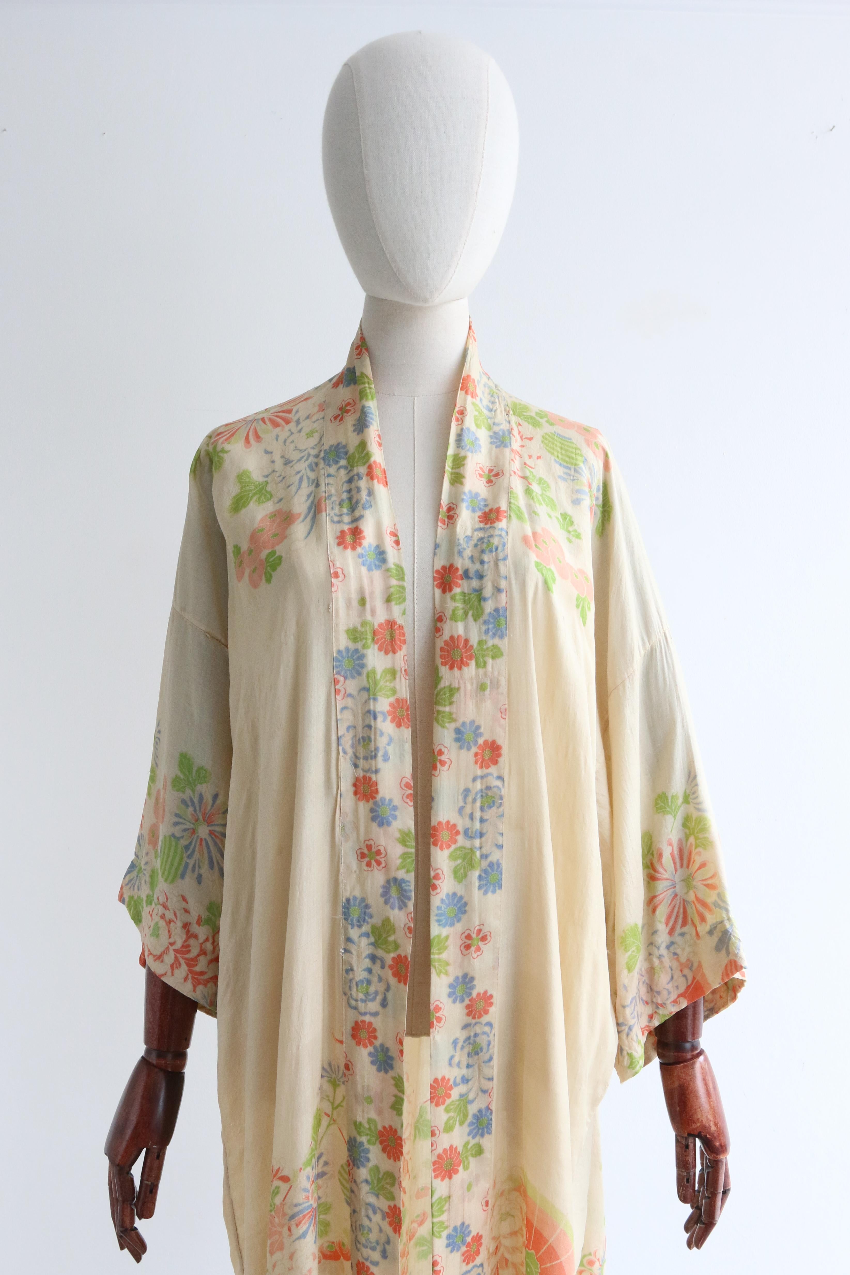 This breathtaking vintage 1920's pongee silk robe, in a muted palette of corals, pinks, greens and blues on a cream toned base, is a rare piece to behold and treasure.

Her traditional cut, boasts 3/4 length kimono sleeves, and an open neckline