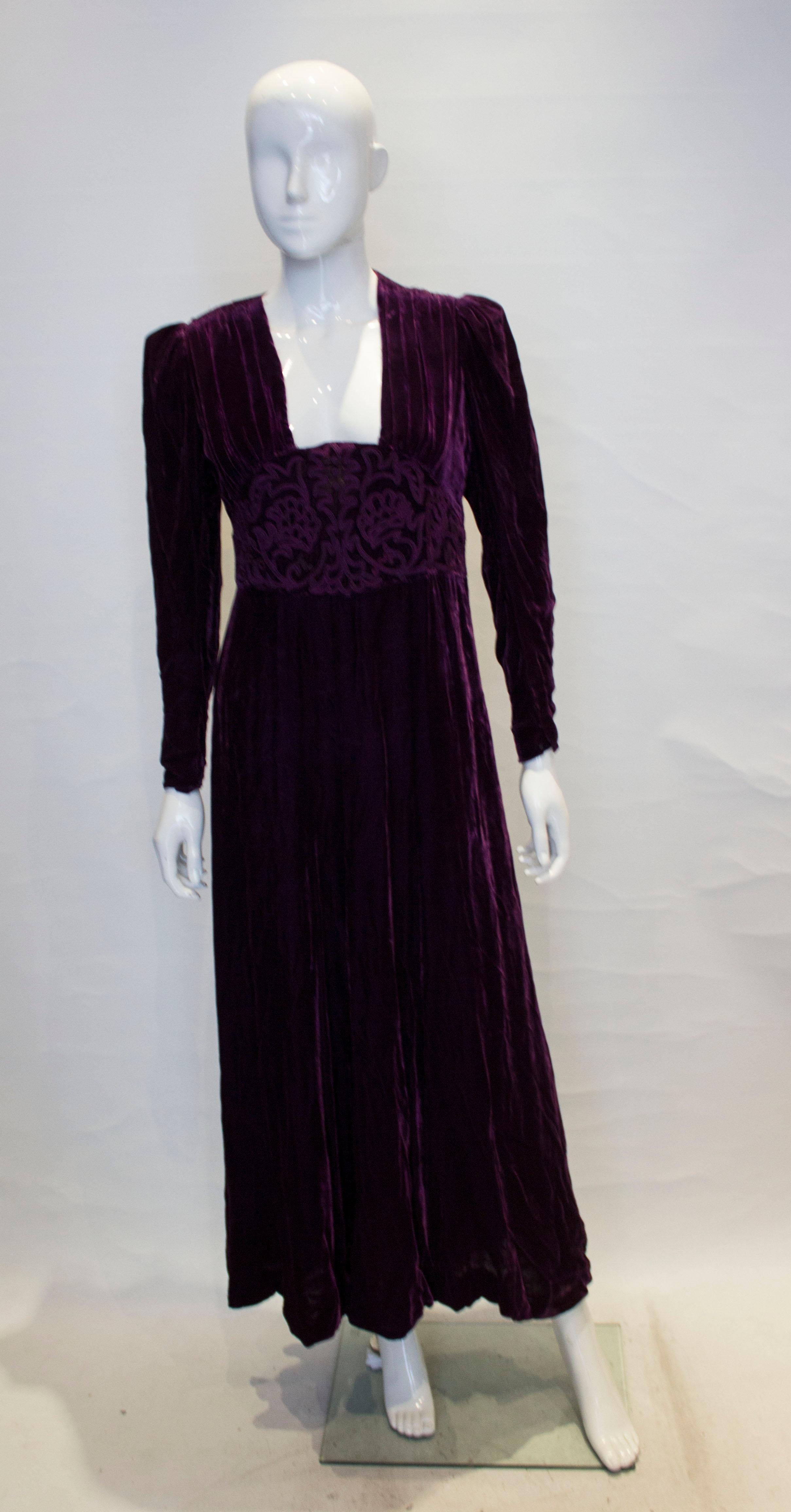 A luxurious vintage velvet gown from the 1920s. The dress has a square neckline with embroidery detail. It has a side opening with hooks and eyes , and popper opening at the cuffs. There is gathering on the shoulders and under the bust. There are