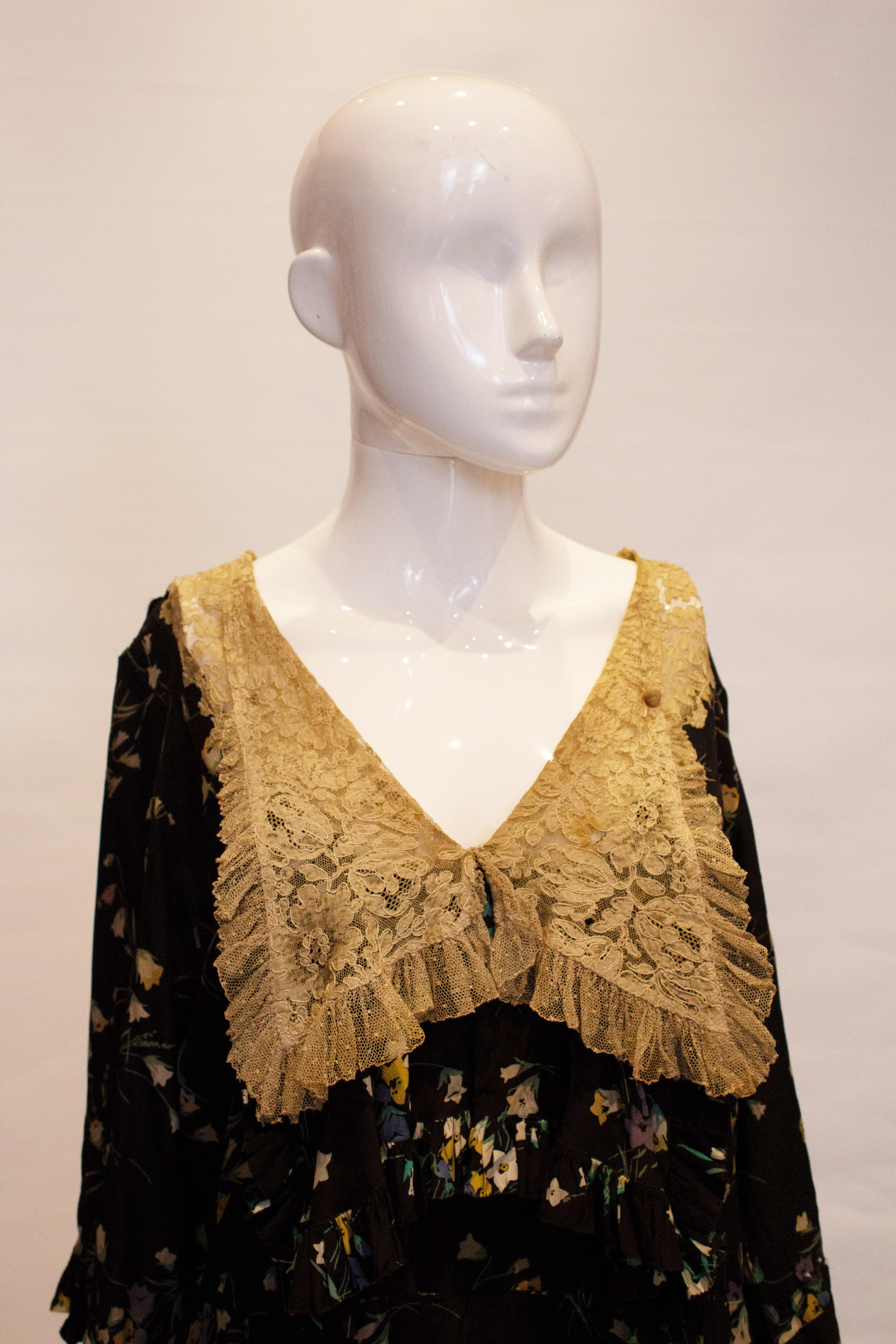 A head turning vintage silk dress from the 1920s. The dress has a black background with a floral print, with lace cuffs and frill arund the neckline. 
Measurements : Bust up to 40'',lenght 51''