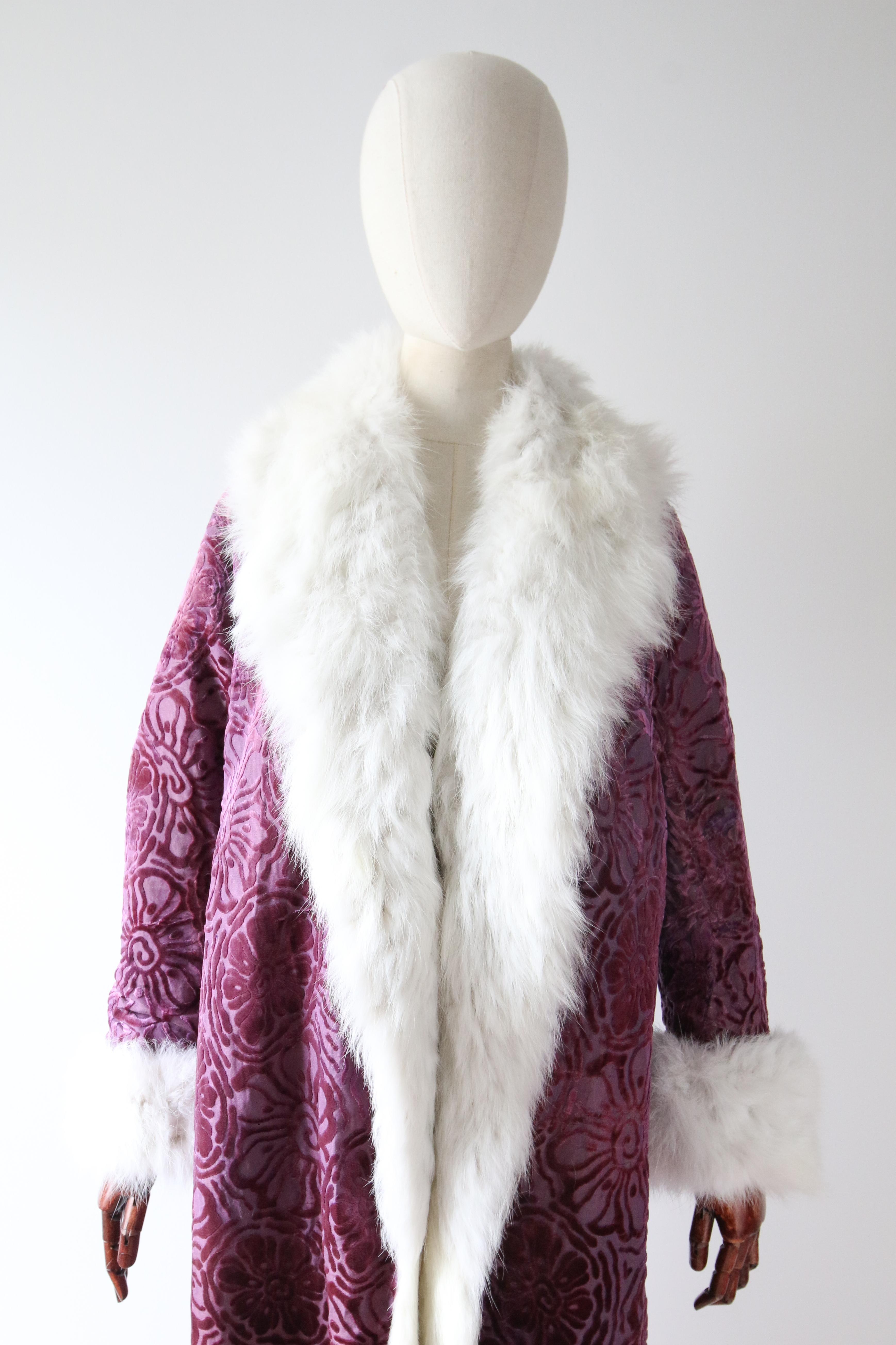 Rendered in the most sumptuous Silk organza & silk velvet Devore, in a palette or violet and purple, boasting a bold floral pattern, and lined in snowy white coney, this original 1920's coat is a marvel to behold. 

The wonderful open cut neckline,