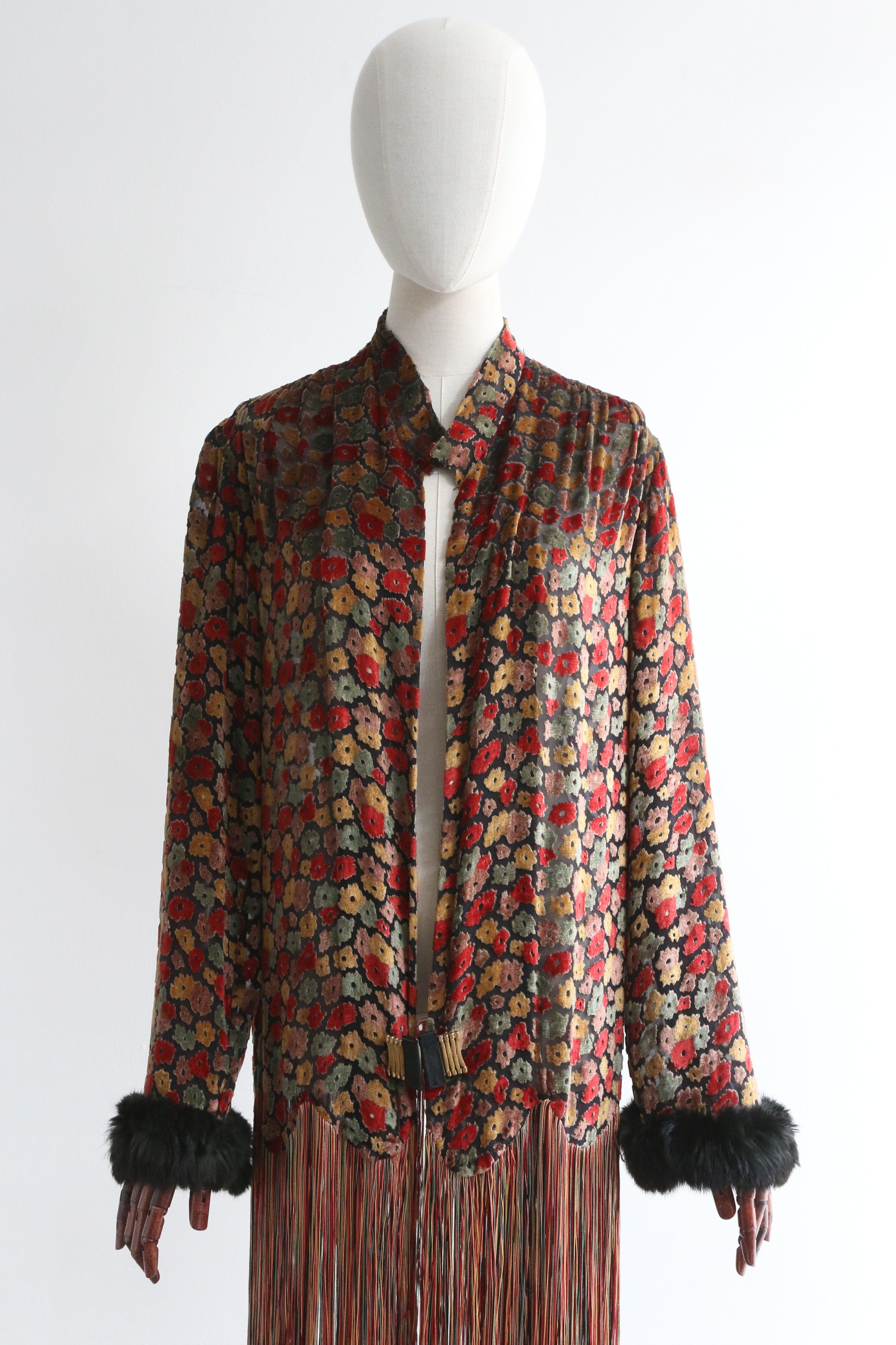 This sumptuous 1920's devoré and silk chiffon jacket, in a floral pattern in autumnal shades of red, green yellow and pink set against a black silk base, edged with longline silk fringing in a matching colour palette, is a rare piece to behold.