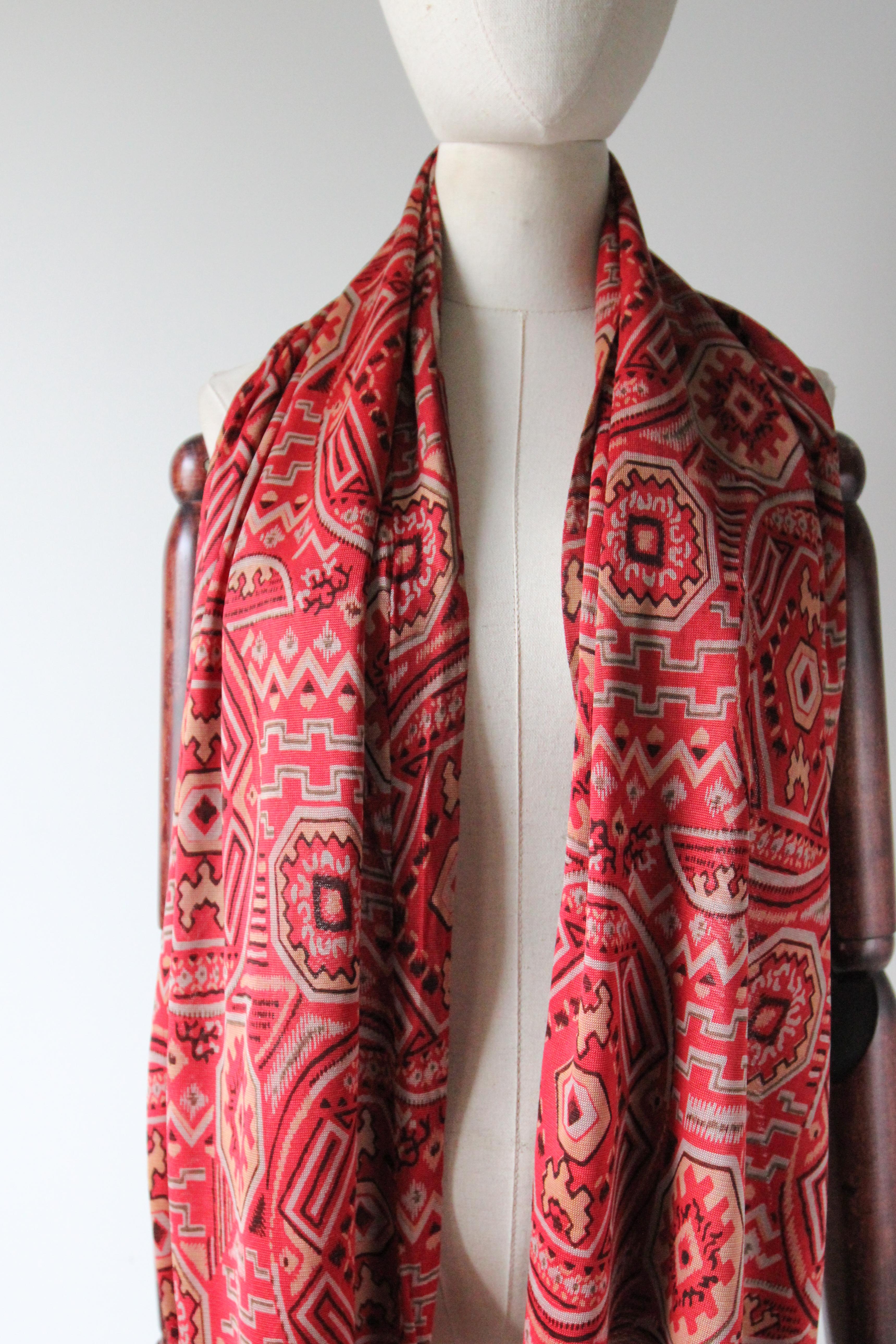 This truly spectacular 1920's silk jersey scarf, in a warm shade of red with a geometric pattern in shades of cream grey and brown,  is the perfect finishing touch to your ensemble. The elegant scarf is edged with silk knotted fringing in matching
