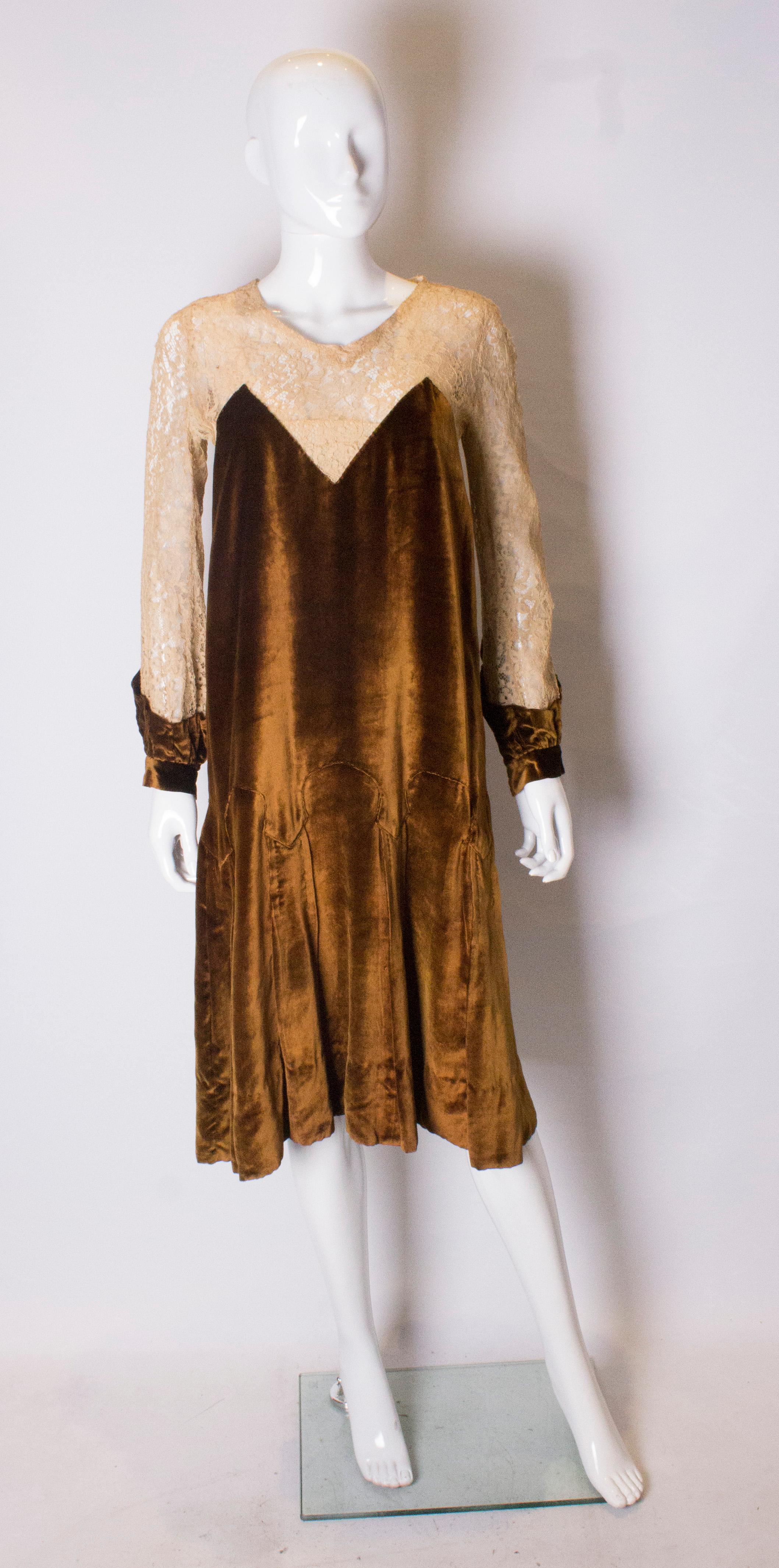 A pretty dress from the 1920s in a  rust /gold colour silk velvet and biscuit colour lace.  The dress has a button opening at the back and is lined to hip leval. The sleeves and yoke are lace and the dress has as drop waist.