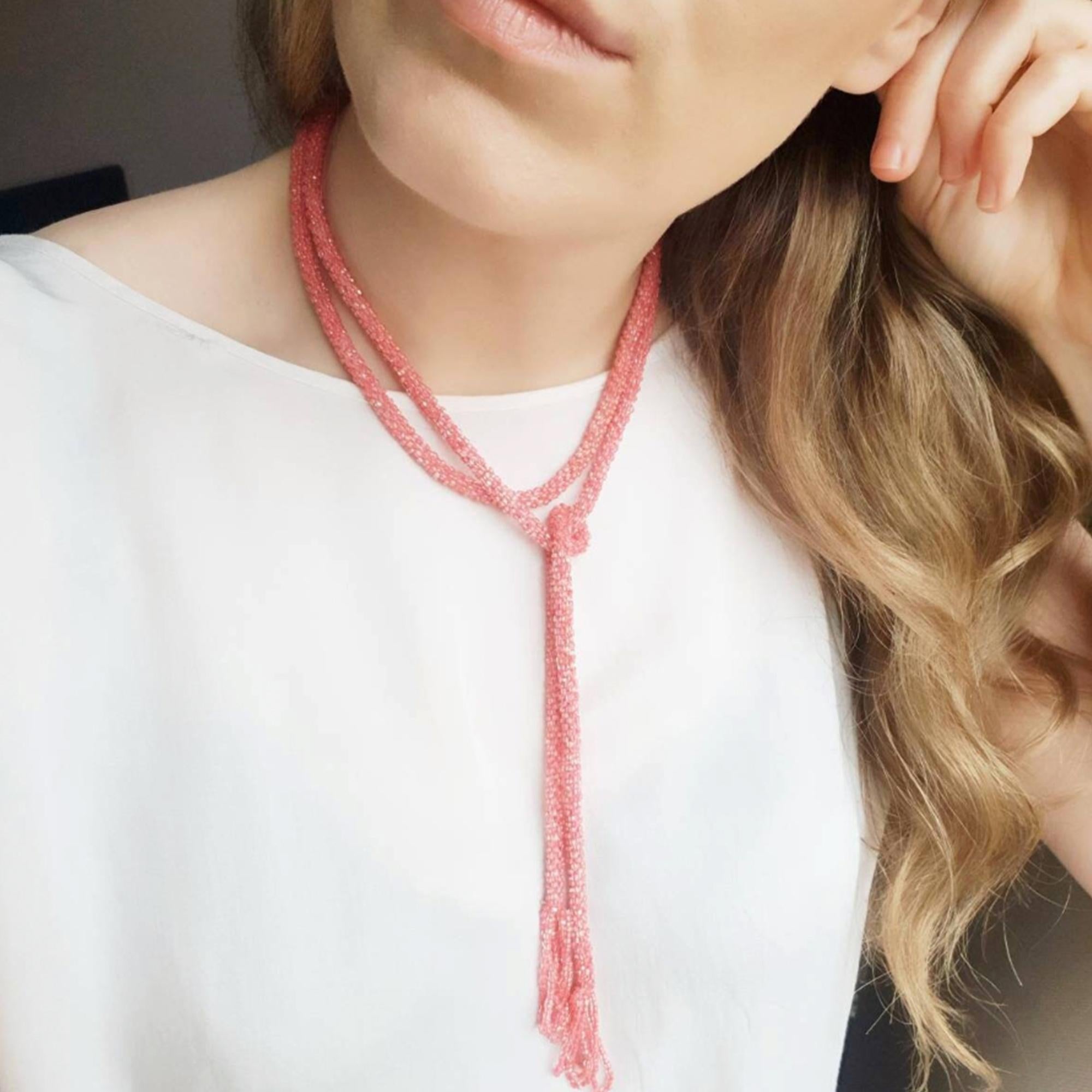 This vintage 1920s flapper necklace features tiny pink glass beads strung into a long, elegant strand finished with tassels. The necklace is designed to be worn by tying the two strands at the front, offering versatility and movement. This