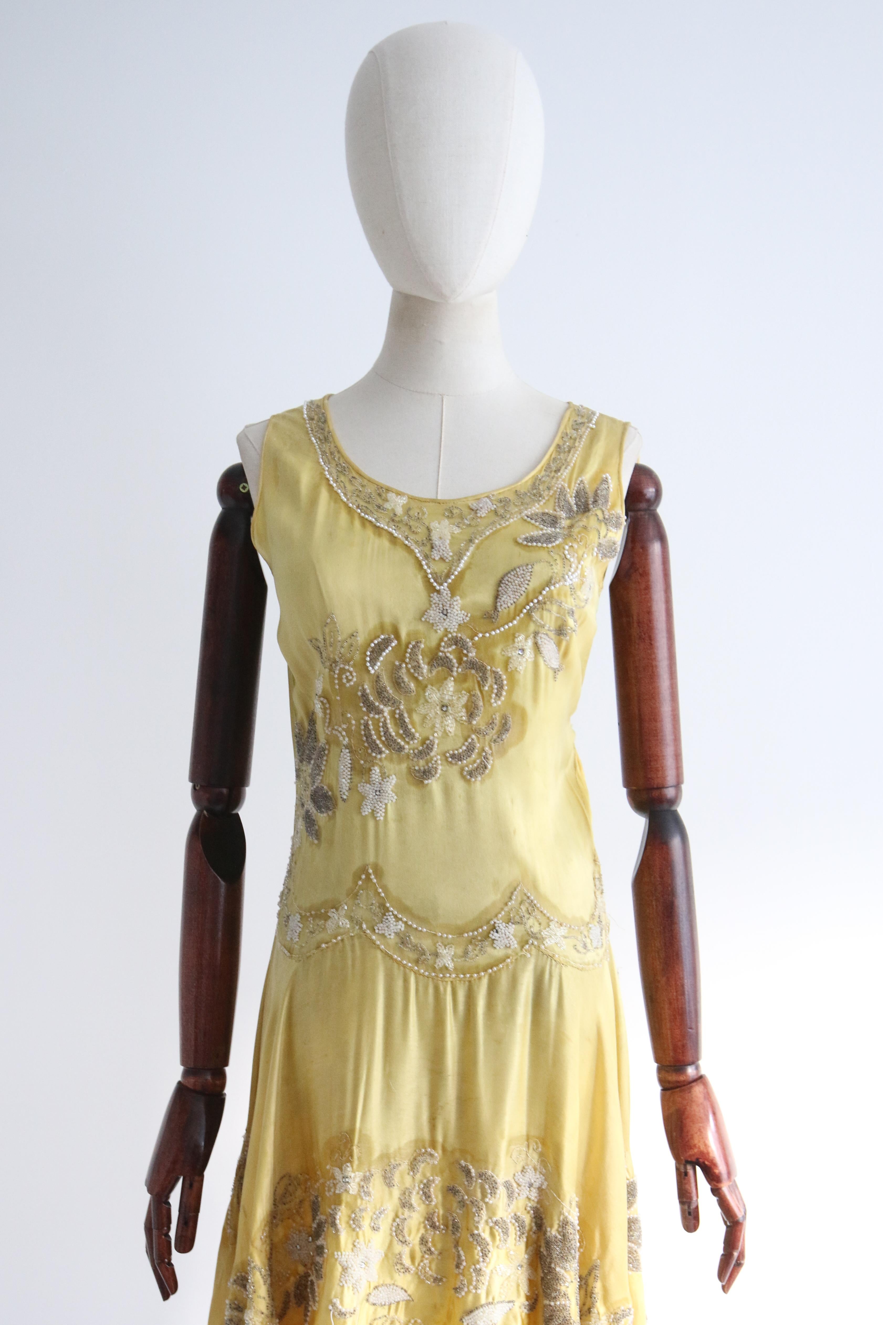 Full of opulent original details, rendered in the most luxurious fashion, this rare 1920's piece is a beauty to behold and never again find.

The rounded neckline of the dress is framed by pipped edgings and accented by a decorative beaded neckline,