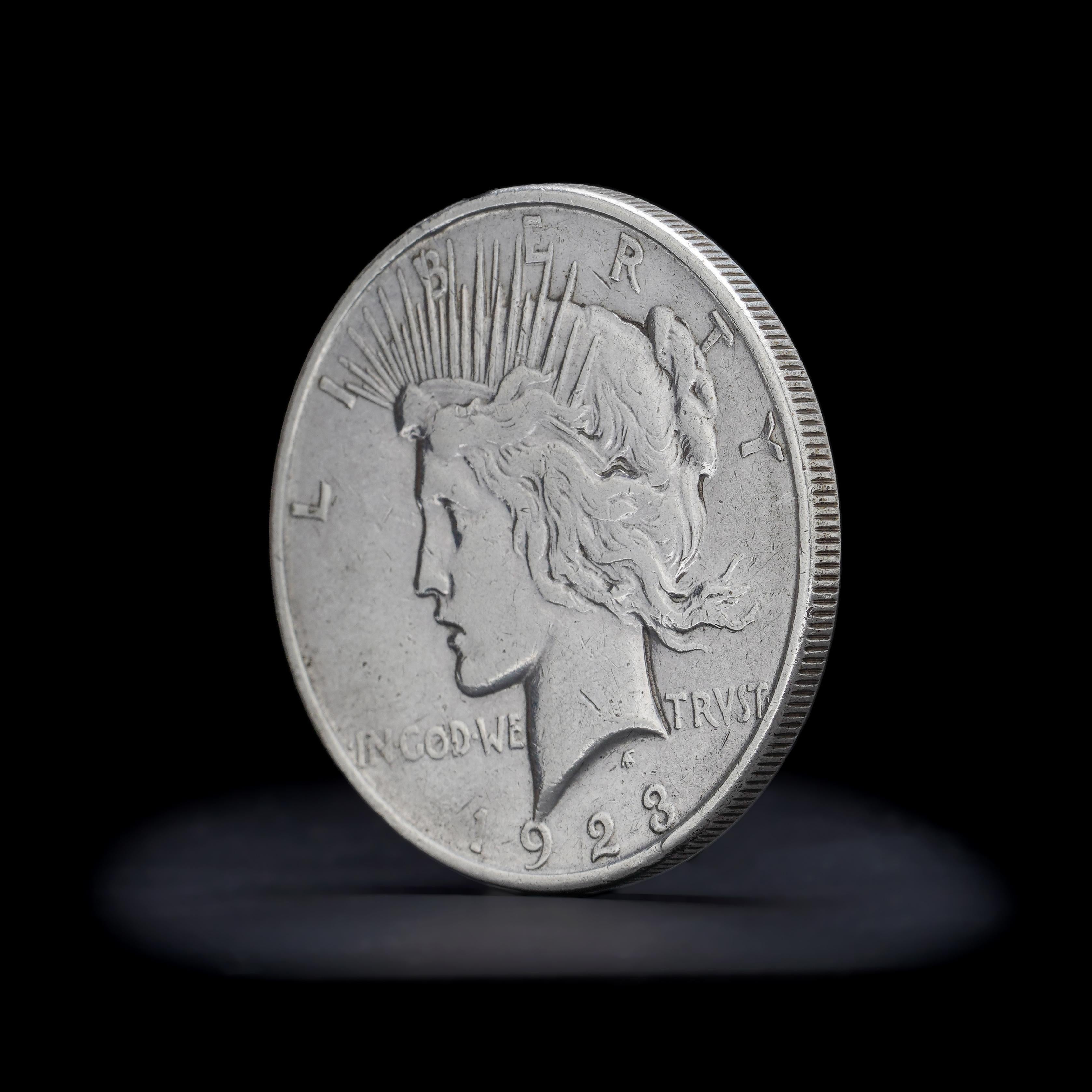 Vintage By  1923 Peace Silver Dollar. 
Hergestellt in den USA, 1923
Münze: Denver
Wird mit einem Reinheitszertifikat für Silber geliefert.

Der Text auf der Vorderseite des Peace Dollar lautet 