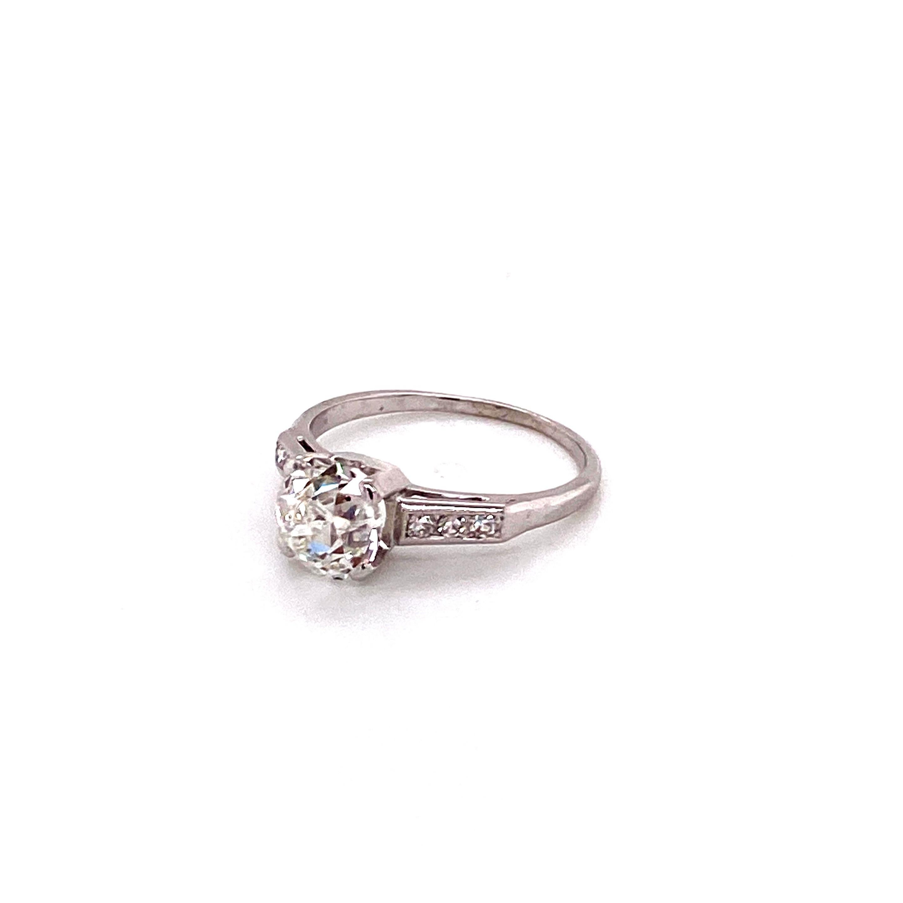 A breathtaking jewel from a glamorous bygone era, this vintage ring dates back to the 1930s. The magnificent centerpiece is an exceptional Old European cut diamond weighing approximately 1.50 carats. Exhibiting a warm antique K color, this