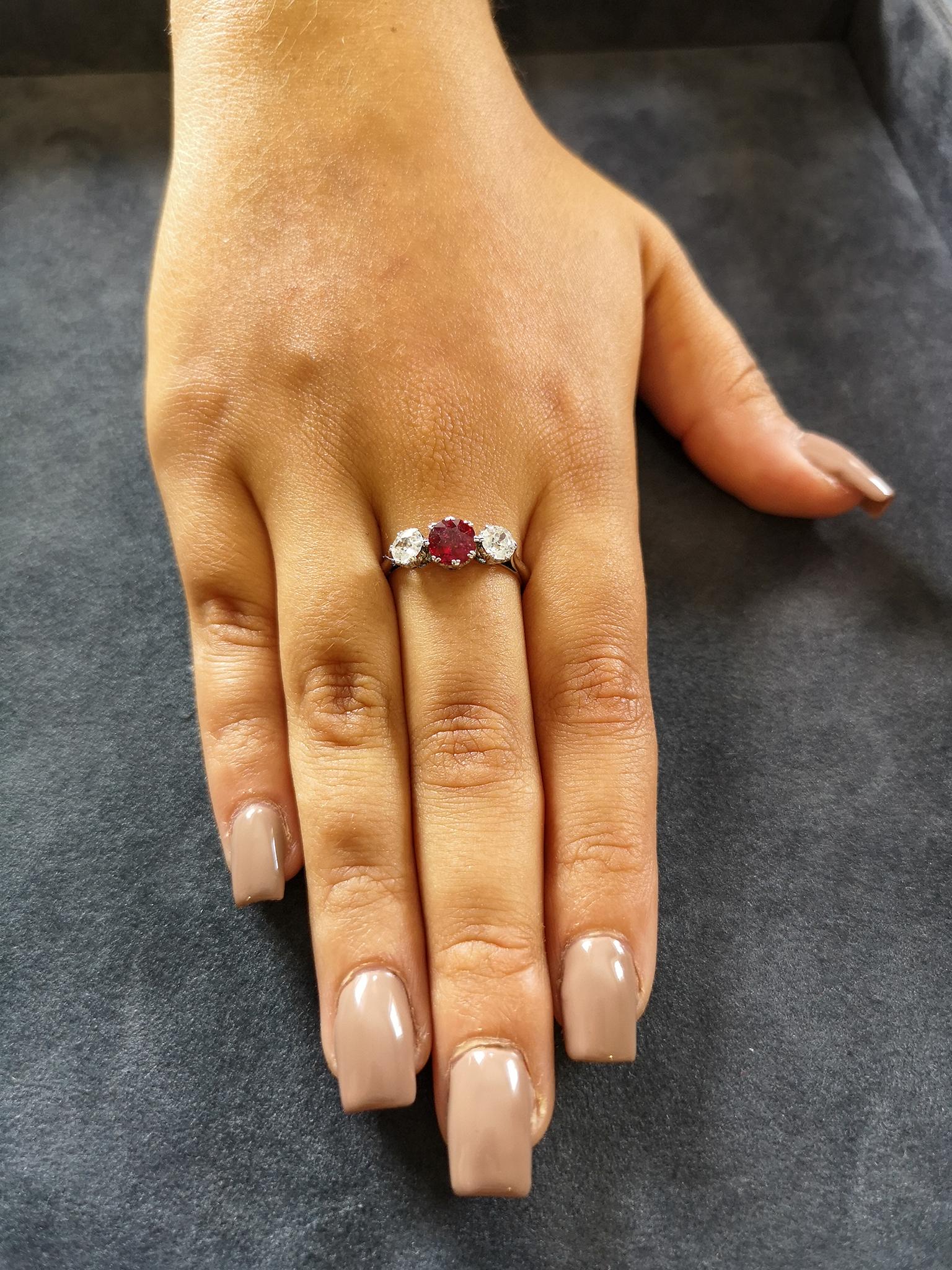 Typical in style of the 1930s, a traditional three stone trilogy ring comprising a central, blood red cushion shaped ruby of approximately 1.00 carat, flanked on each side by a single old-cut diamond, totaling approximately 0.80 of a carat, H-I