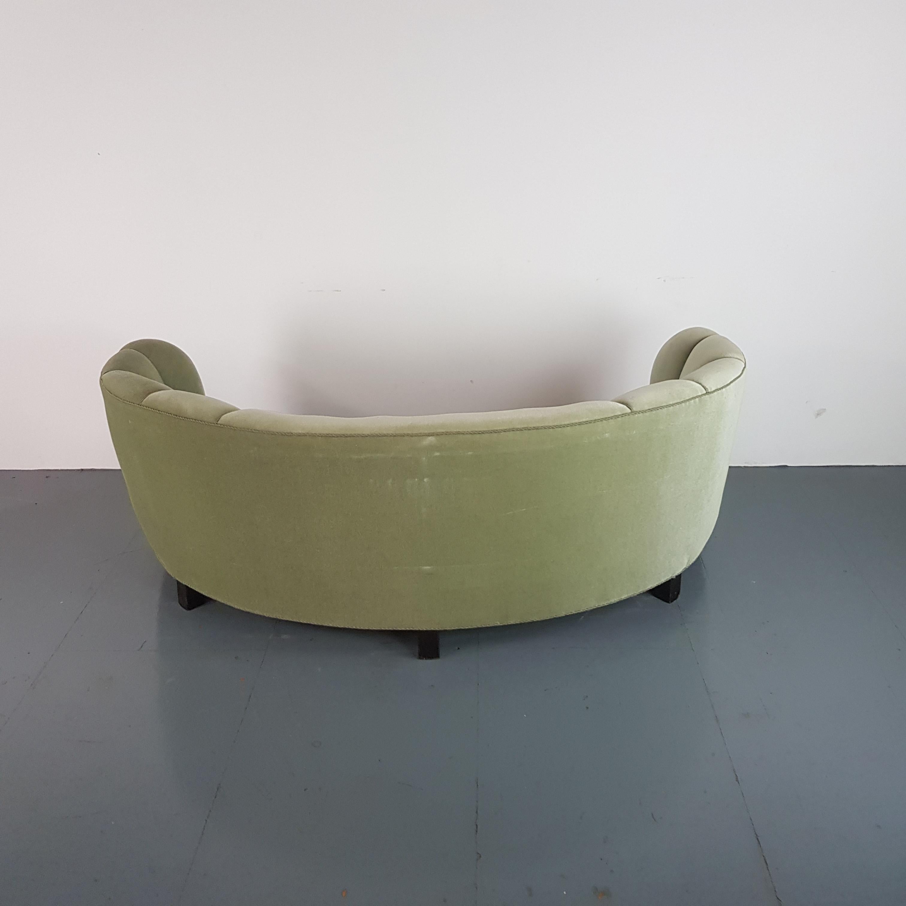 Gorgeous Danish curved Banana sofa upholstered in its original green velvet fabric, with wooden legs.

Approximate dimensions:

Height: 74 cm

Width: 190 cm

Depth: 108cm.

Some wear, as to be expected in a vintage item, but nothing