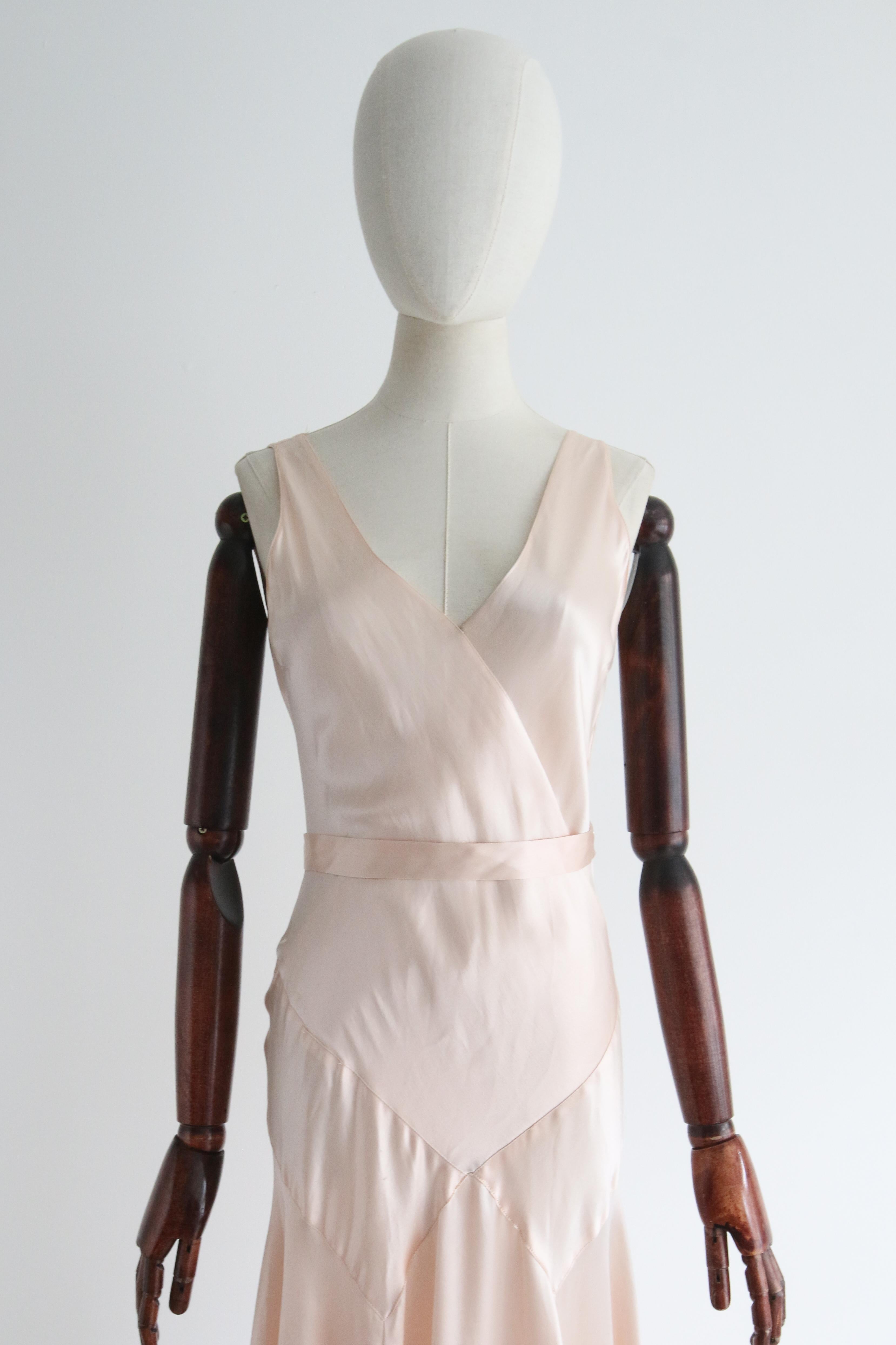 A true beauty to behold. This original 1930's dress, rendered in a soft ballerina pink satin, showcasing the incredible pointed seam designs of the 1930's, is a timeless beauty to behold. 

The V shaped cross over neckline of the dress, draws