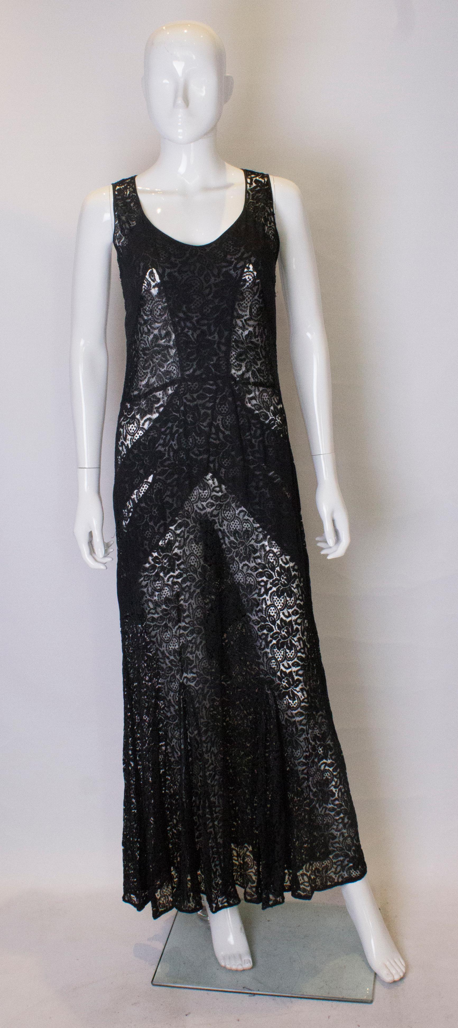 Ein schickes schwarzes Spitzenkleid aus den 1930er Jahren. Das Kleid hat vorne einen Rundhalsausschnitt, ist mit Spitzeneinsätzen versehen und hat einen Spitzenrock. Der Saum ist mit einem Band eingefasst.