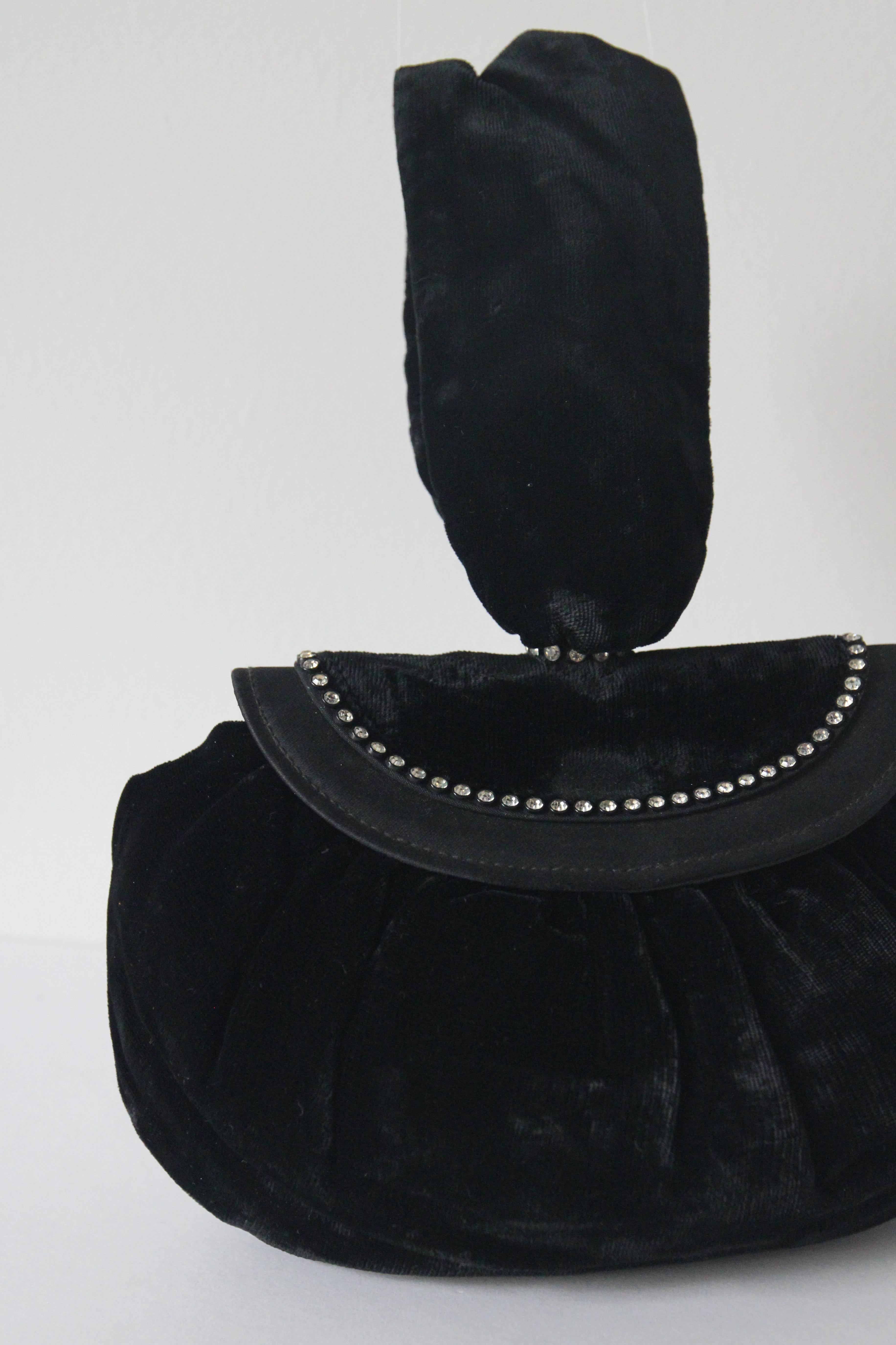 Ce délicat sac de soirée vintage des années 1930 en velours de soie noir, avec des accents de strass argentés et des détails en soie noire, est l'accessoire parfait pour tout amateur de vintage.

L'élégante poignée en velours de soie rejoint le haut