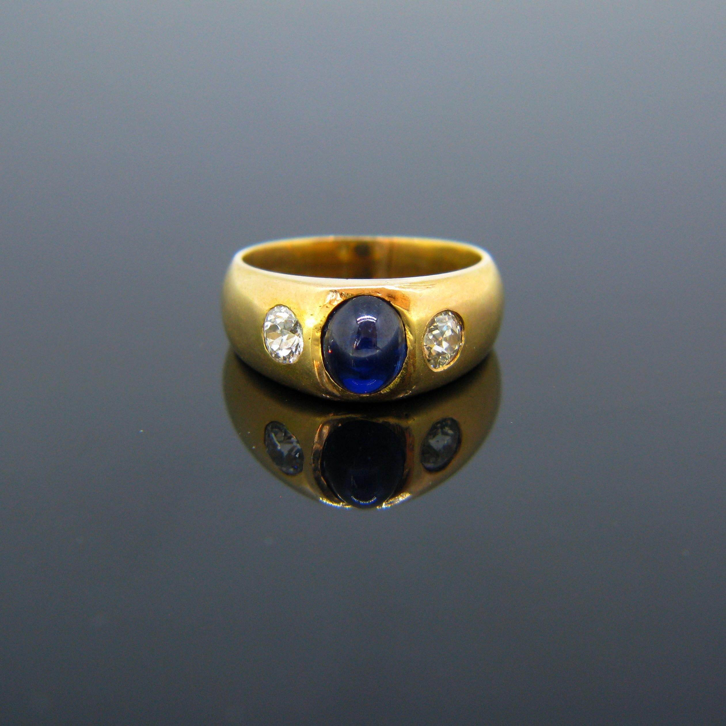 This beautiful vintage gypsy ring is set with a cabochon cut sapphire weighing approximately 2.50ct and adorned with two old cut diamonds each weighing around 0.30ct. It is fully made in 18kt yellow gold and is marked with the