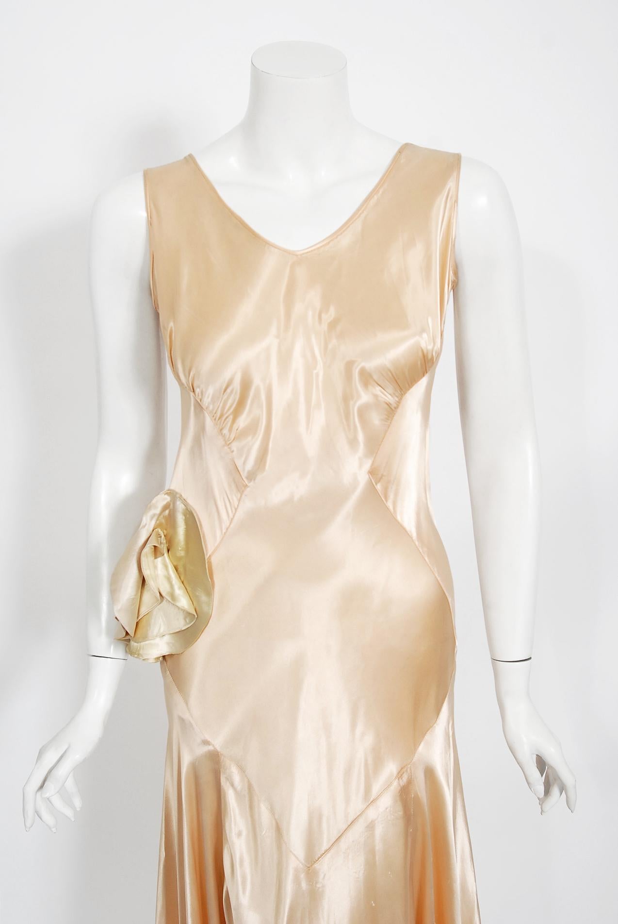 A breathtaking 1930's custom-made champagne silk satin gown from the Old Hollywood era of glamour. There is so much detail, you can tell this masterpiece was created with love and care. The bodice has a seductive sculpted v-cut plunge sleeveless