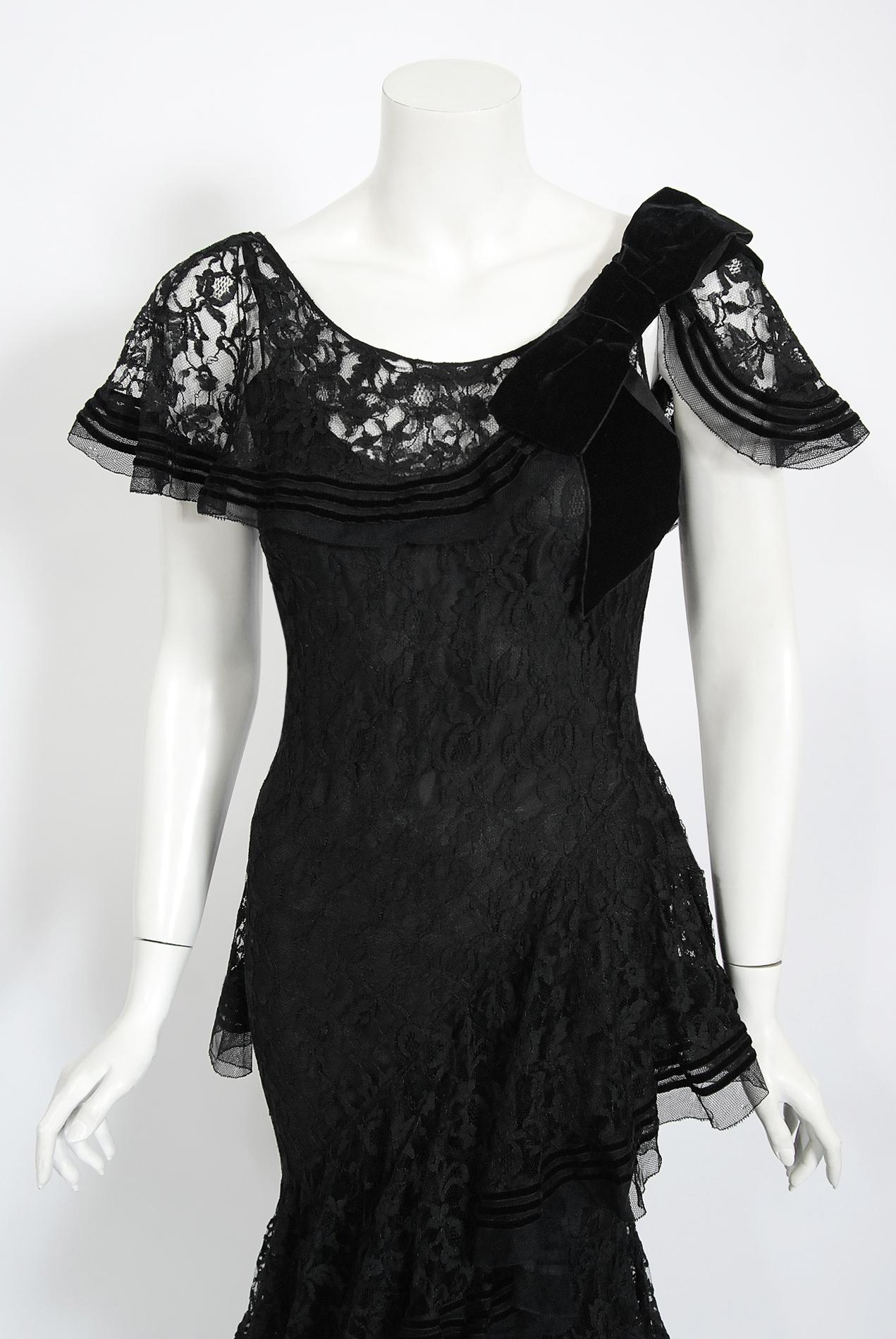 Undiminished by time, this mid 1930's black lace couture gown still casts its magical spell. This exceptional French beauty is fashioned in the highest quality black floral patterned lace that has been carefully embellished with velvet striped