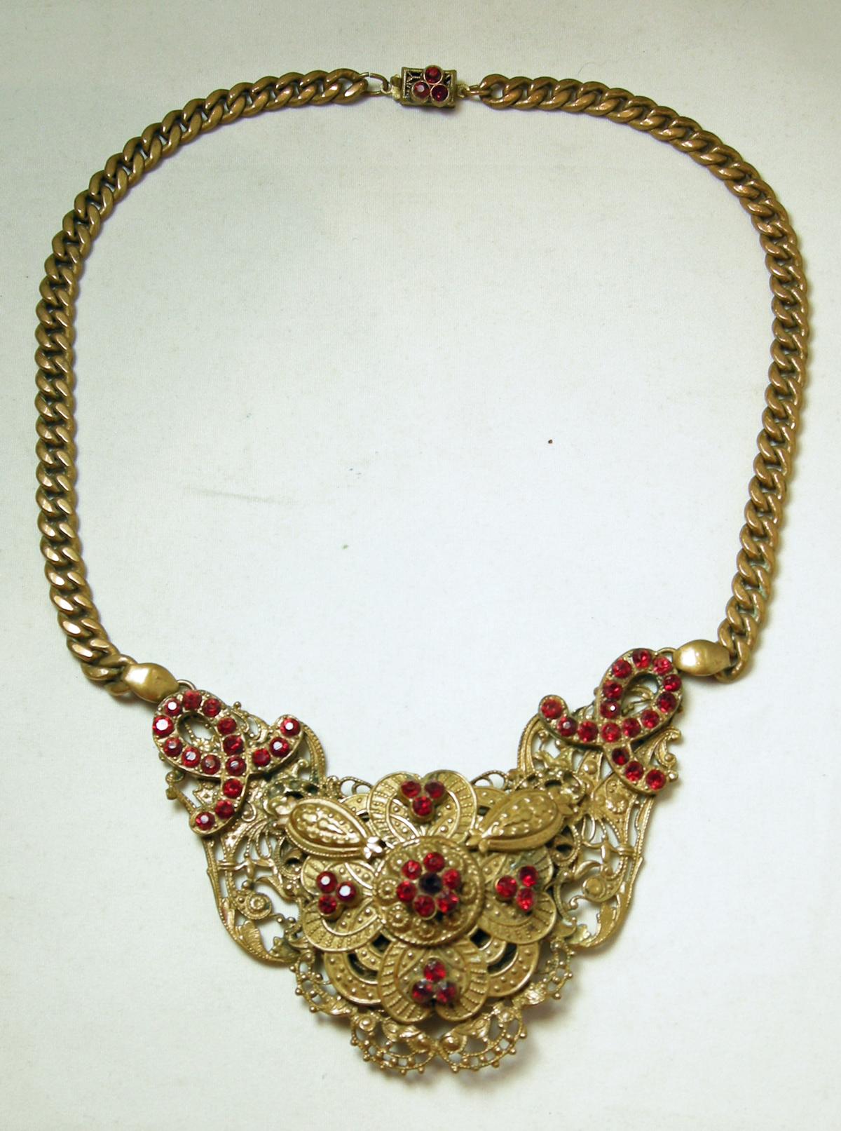 It’s getting harder to find necklaces like this because collectors don’t want to let them go.  It has a 3-dimensional centerpiece with a floral design with red crystals.  It has a heavy link chain with a slide in clasp.  It is 15” and the