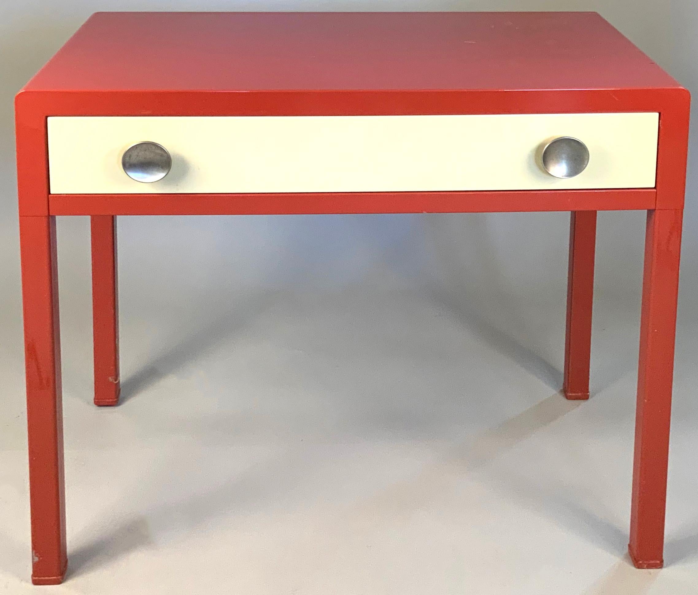 a nice example of this rare desk designed by Norman Bel Geddes for Simmons. the case colored in a red persimmon color, with the drawer front in ivory. the drawer with its original concave brushed aluminum drawer pulls. the top has age expected wear,