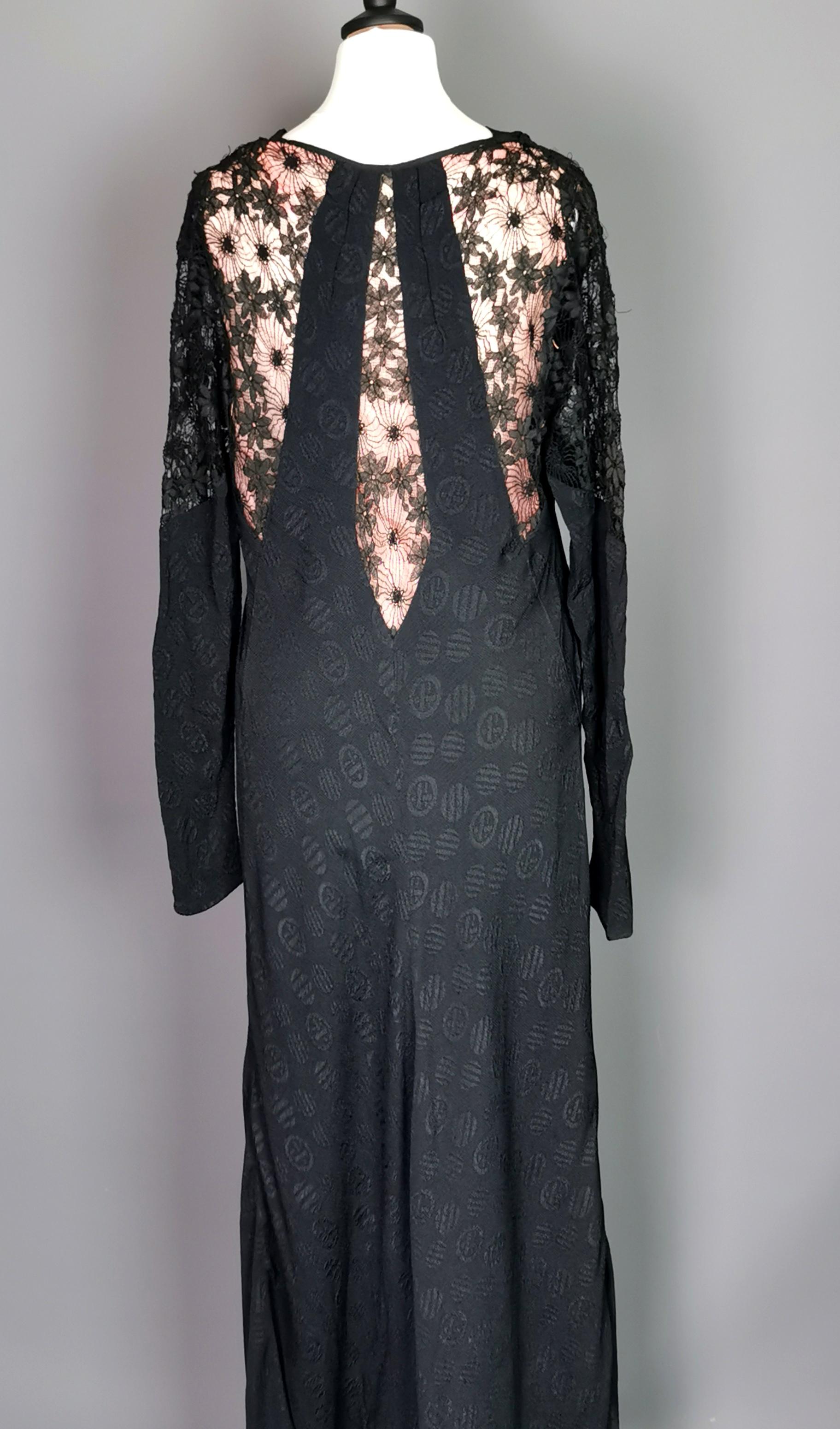 Ein wunderschönes, verführerisches und vampirhaftes Vintage-Kleid aus schwarzer Viskose aus den 1930er Jahren mit Spitzendetails und einem rosa Rücken.

Ein langärmeliges Kleid mit gerolltem Halsausschnitt, das in der Taille eingeschnürt ist, mit