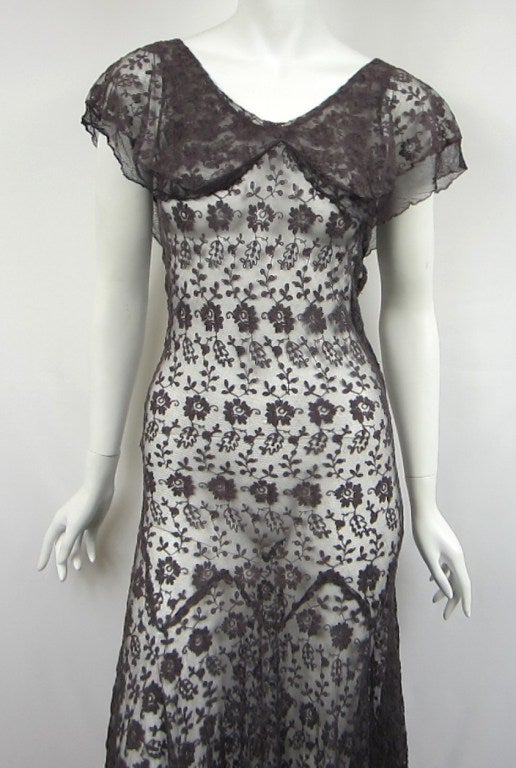 Beautiful and unique 1930s dress. Done completely in sheer mesh with a embroidered Floral Motif. Flutter collar and sleeves. Snaps up the side. Color is a gray purple tone. Wear as a peek a boo or wear a slip. Measures up to 31 Bust -- 25Waist-- 34