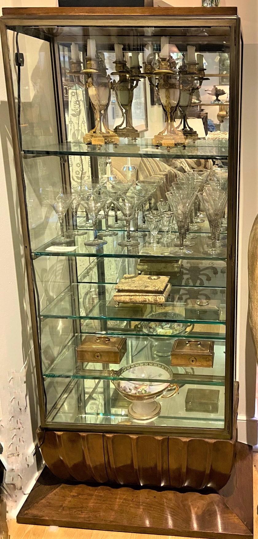 Vintage 1930s Art Deco display case made in nickle plated with original matching adjustable four glass shelves, mirrored back and bottom shelf, functioning lighting, sides and glass door opening, carved walnut finish base.