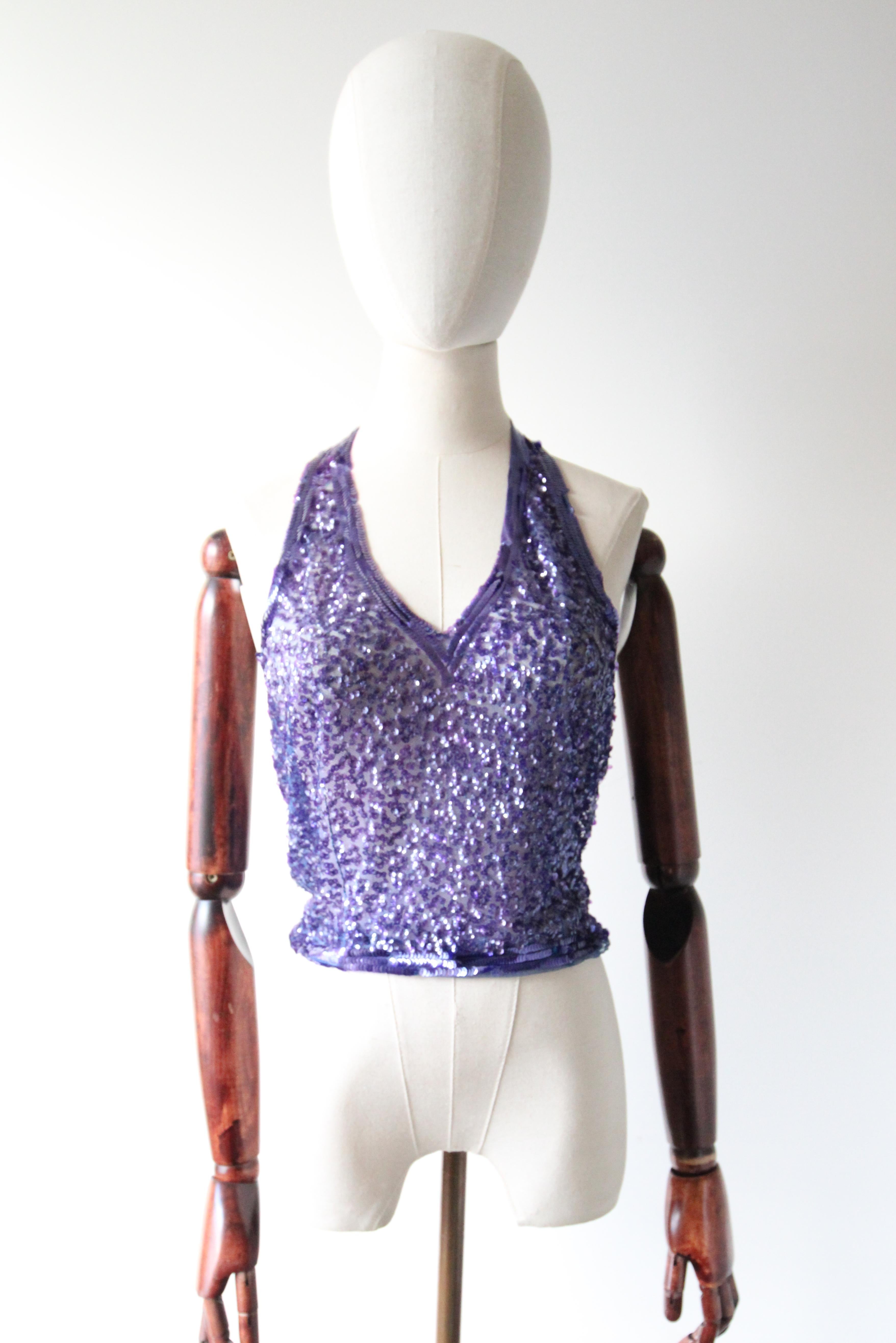 Diese wirklich spektakuläre französische Bluse aus den 1930er Jahren mit dämmerungsviolettem Paillettenbesatz auf französisch-blauem Baumwollstoff ist eine Rarität und das perfekte Teil für Ihre Cocktailgarderobe.  

Der Neckholder wird im Nacken