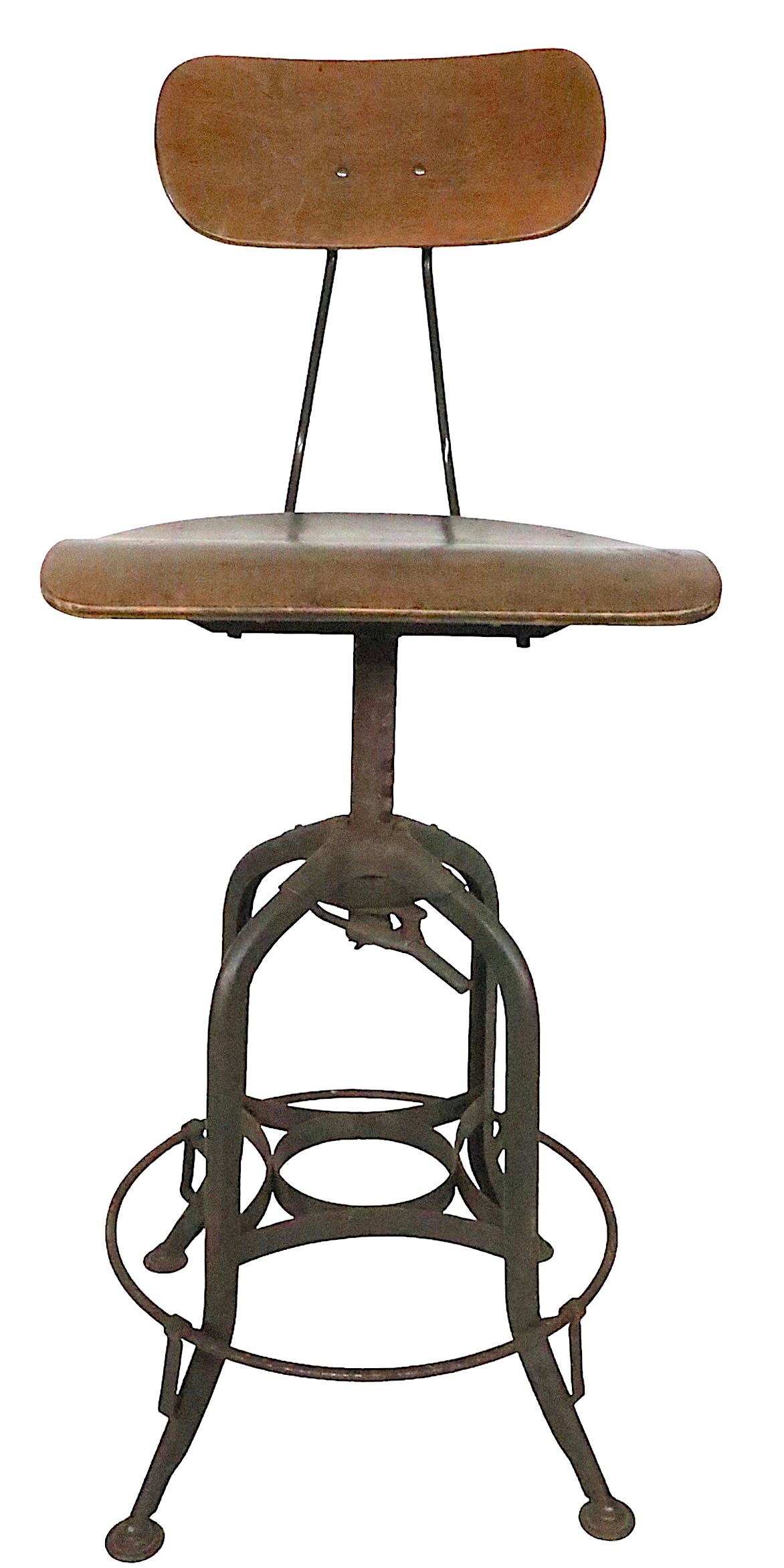 Classic adjustable work stool by the Toledo Metal Furniture Company, Made in USA, circa 1930s. The stool features a swivel seat, and a back rest which tilts and is also adjustable in height. The seat height adjustment allows seat to be in a low