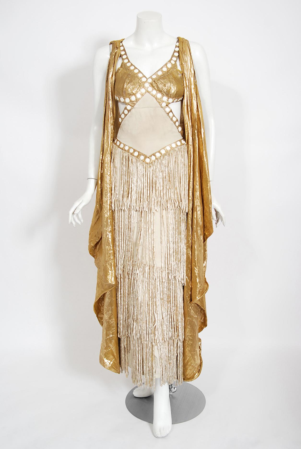 A truly unique and ultra seductive metallic gold lamé burlesque stage gown dating back to the late 1930's. This seductive showstopper is a beautifully constructed with yards of draped gold lamé and ivory silk crepe lined Victorian chenille-fringe.