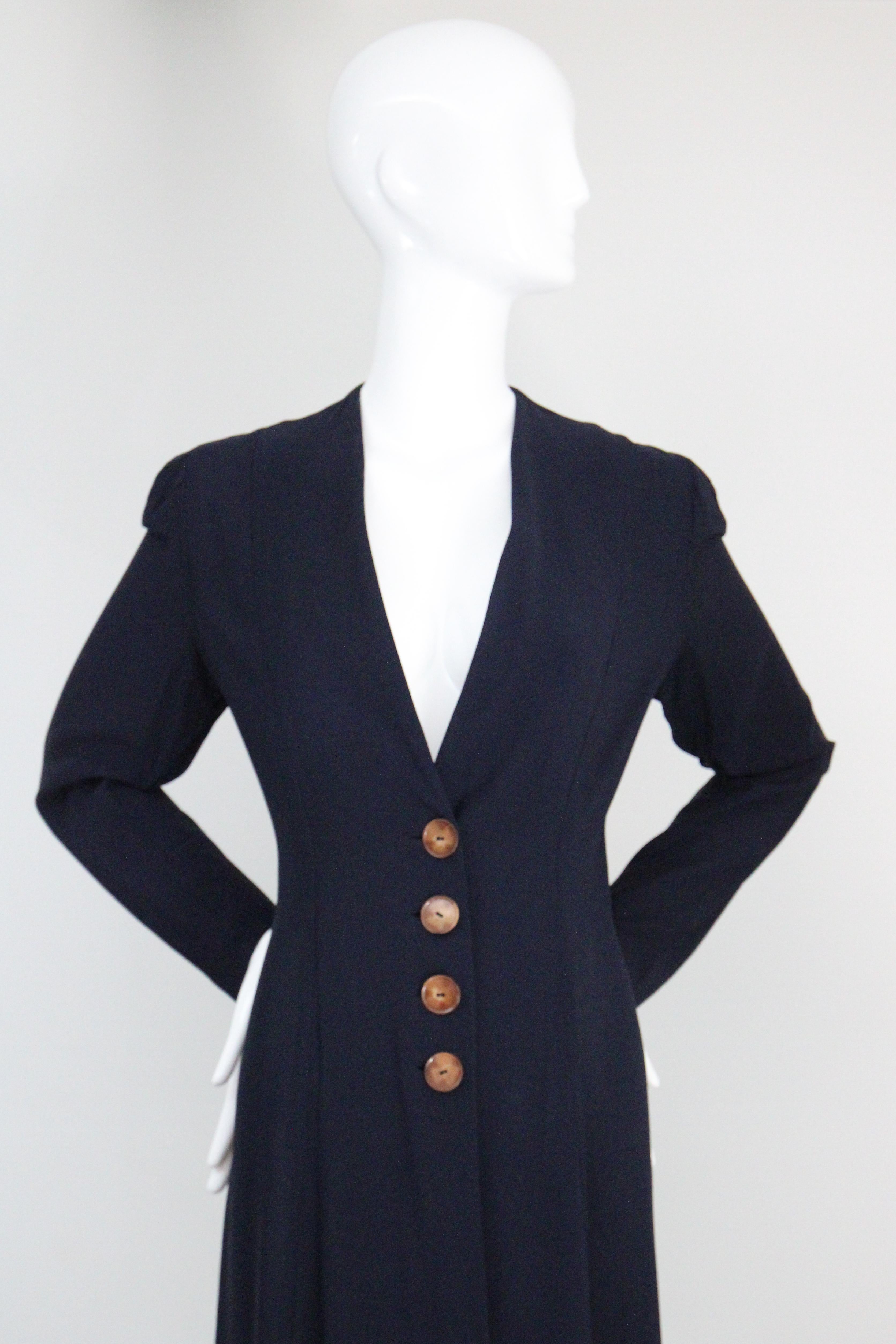 This truly magnificent 1930's navy blue spring coat, accented by mock tortoiseshell buttons, is the perfect addition to your seasonal vintage wardrobe. 

The deep V neckline is framed by a simple shoulder line, from which Princess seams begin and