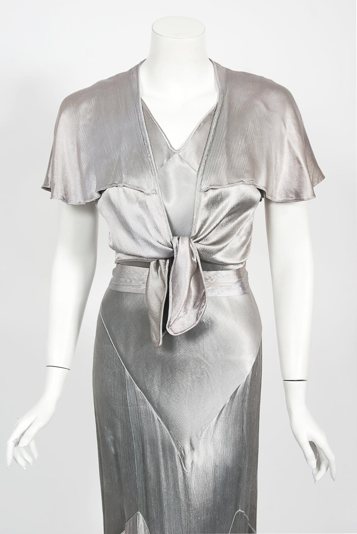 An ethereal shimmering silver silk satin bias-cut gown from the 1930's Old Hollywood era of glamour. So Jean Harlow! I adore the sleeveless belted bodice with matching flutter-sleeve bolero jacket. This figure flattering garment nips in at the waist