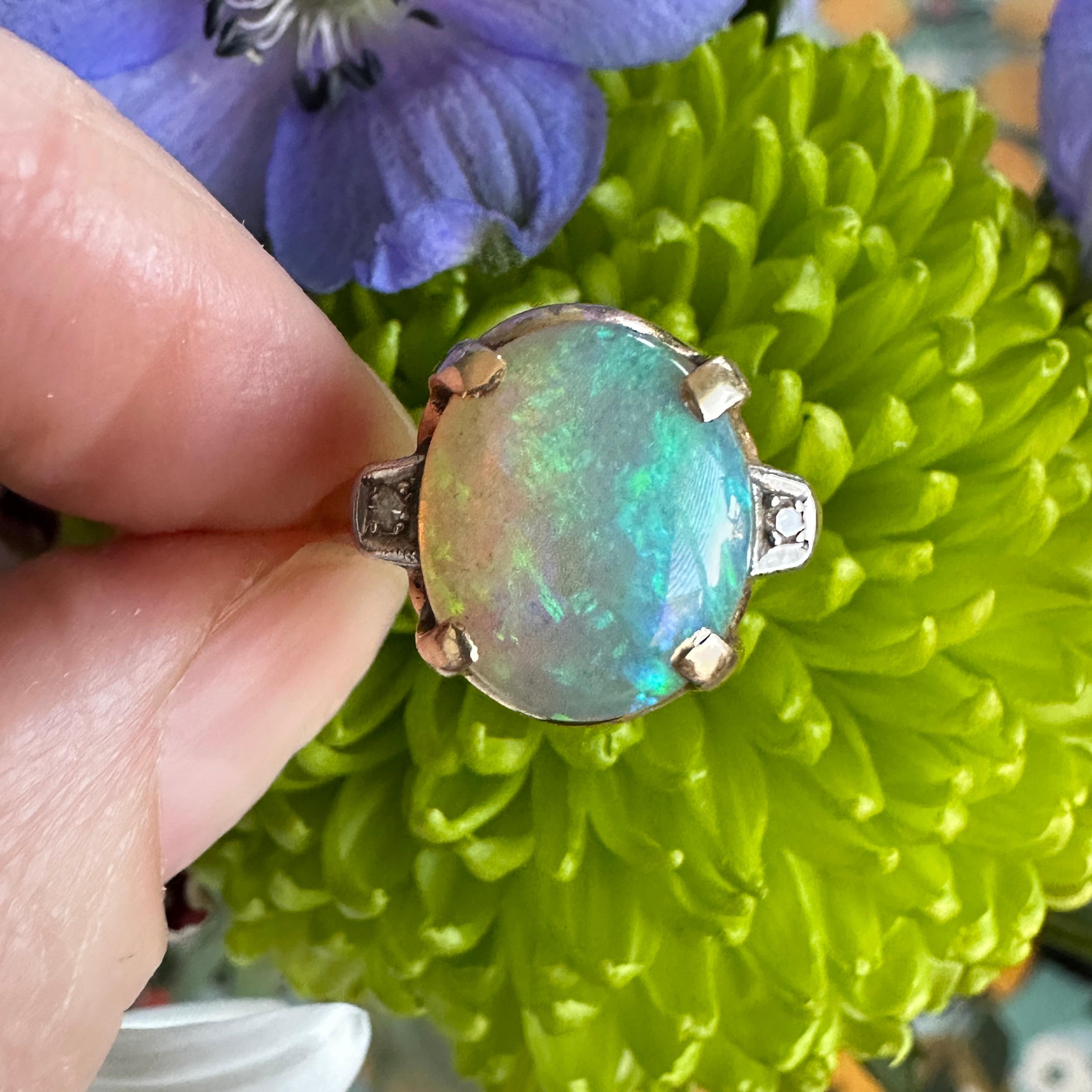 Details:
Sweet Vintage 1930's opal and diamond ring set in 14K yellow gold! The full spectrum opal measures 12.5mm x 10.5mm, and has blues, greens, pinks and yellows. There are two 1.75mm diamonds adorning the shoulders of the band. The interior of