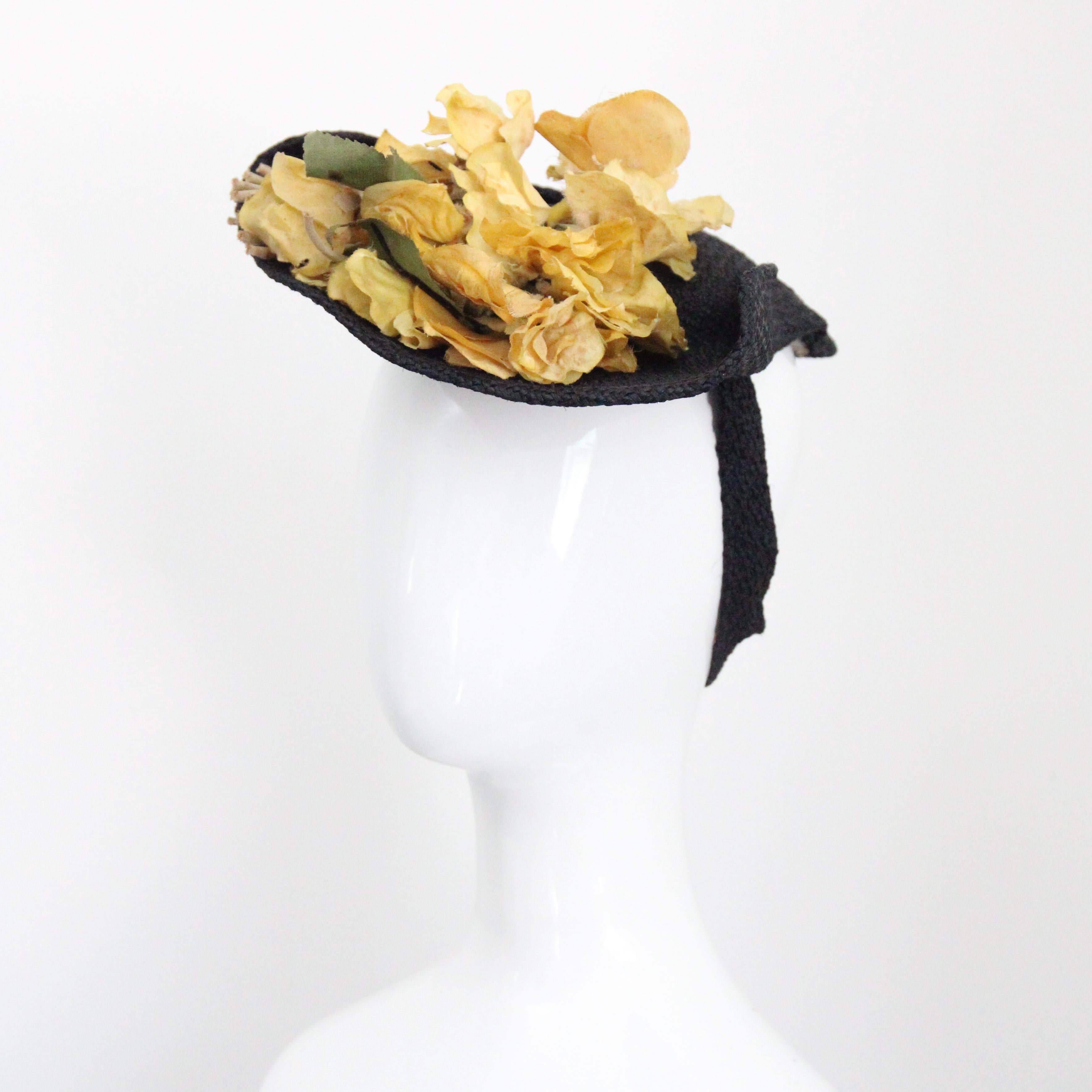 This beautiful and timeless 1930's straw and floral hat, is a rare piece to behold. 
The elegant black woven straw base, boasts an oval shaped crown which is framed by a soft turned down brim which is sewn into place along either side of the crown.
