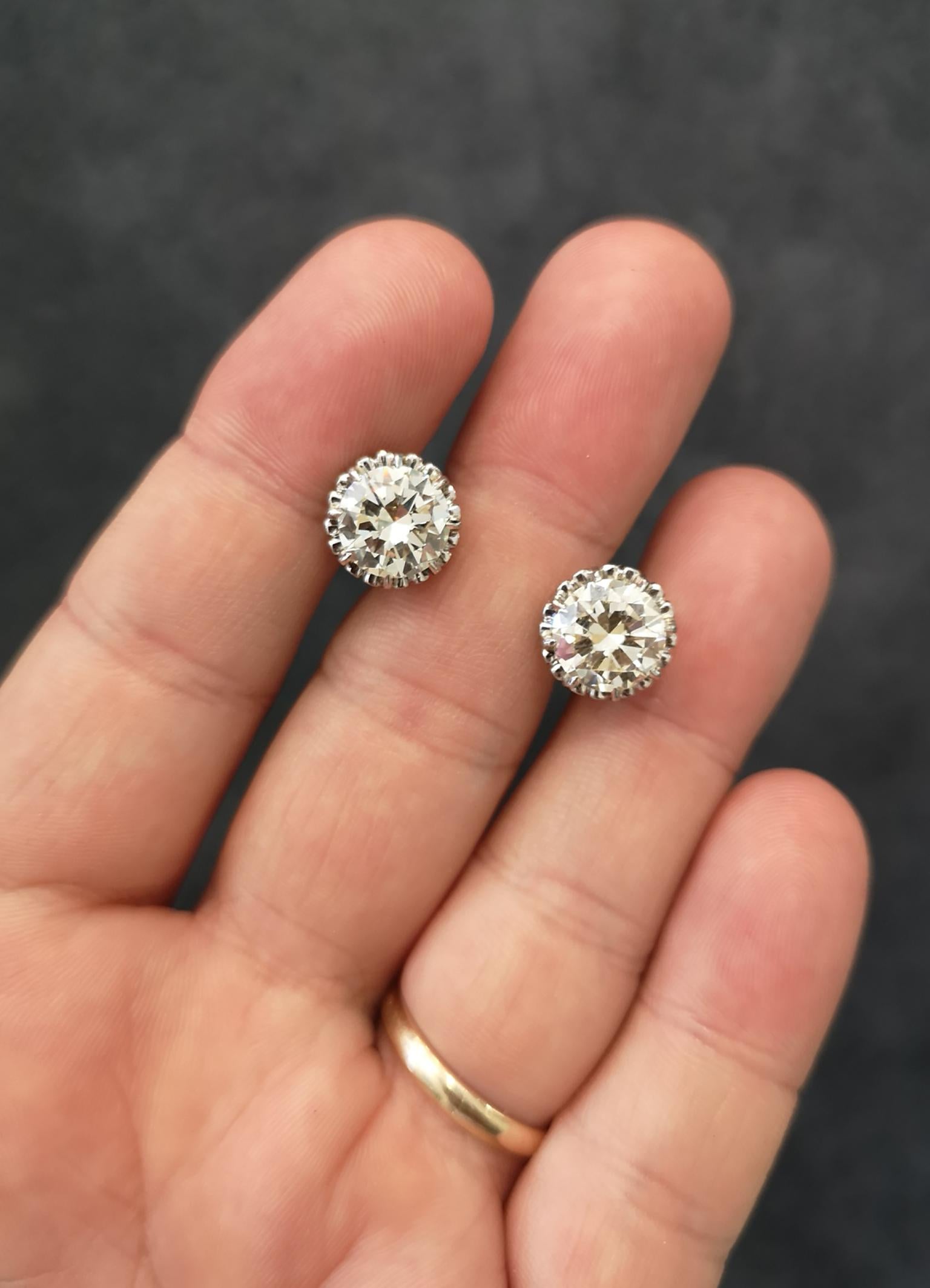Astonishing pair of diamond ear studs. Exceptionally well matched brilliant-cut diamonds, each approximately 3.00 carats, K-L colour, VVS clarity. Mounted in eight, pointed platinum claws, framed with a fancy scalloped platinum border. Posts with
