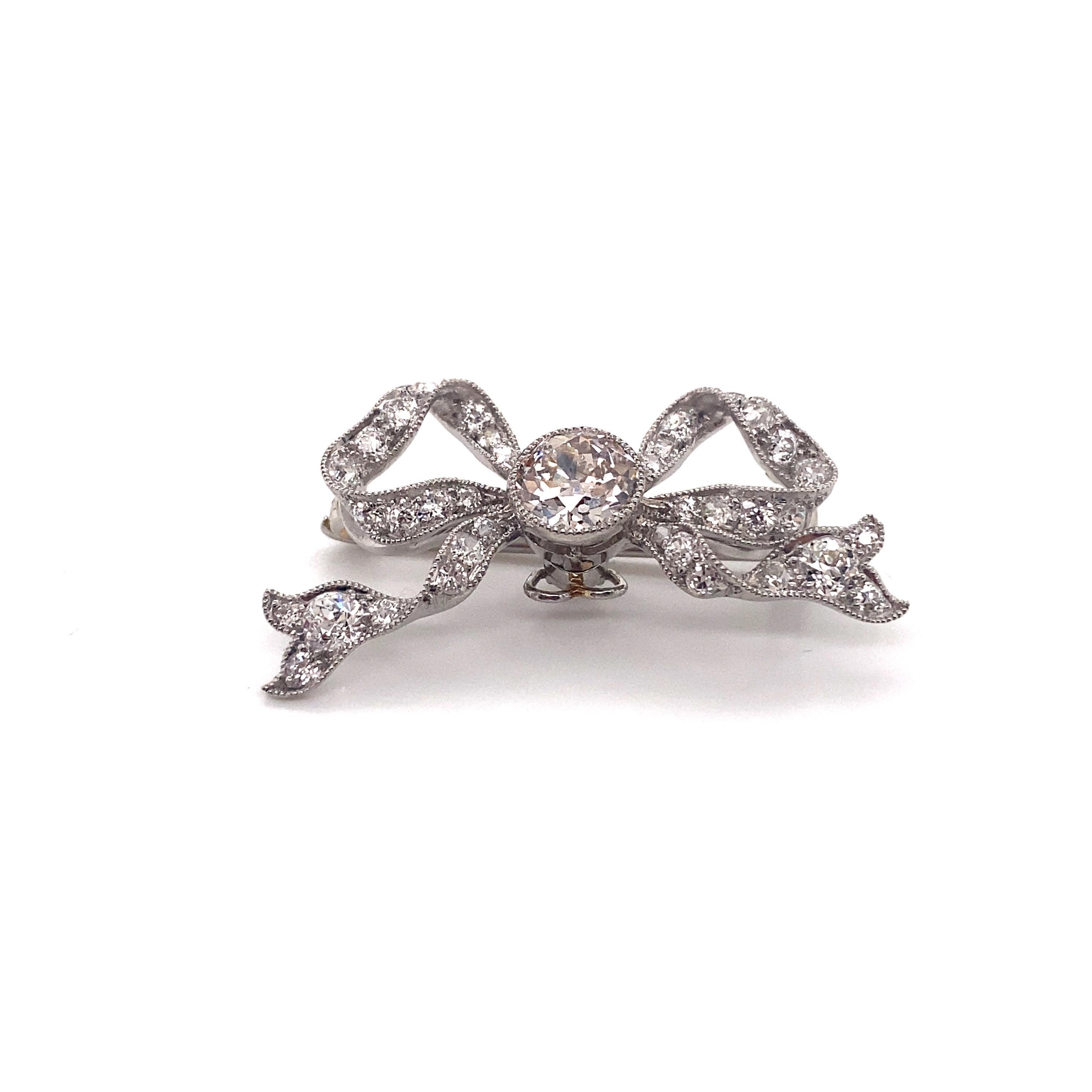 This exquisite vintage pin from the 1930s is a true testament to the exquisite craftsmanship of its era. Rendered in lustrous platinum, it showcases the timeless elegance of the Art Deco period with its distinctive bow design.

The centerpiece of