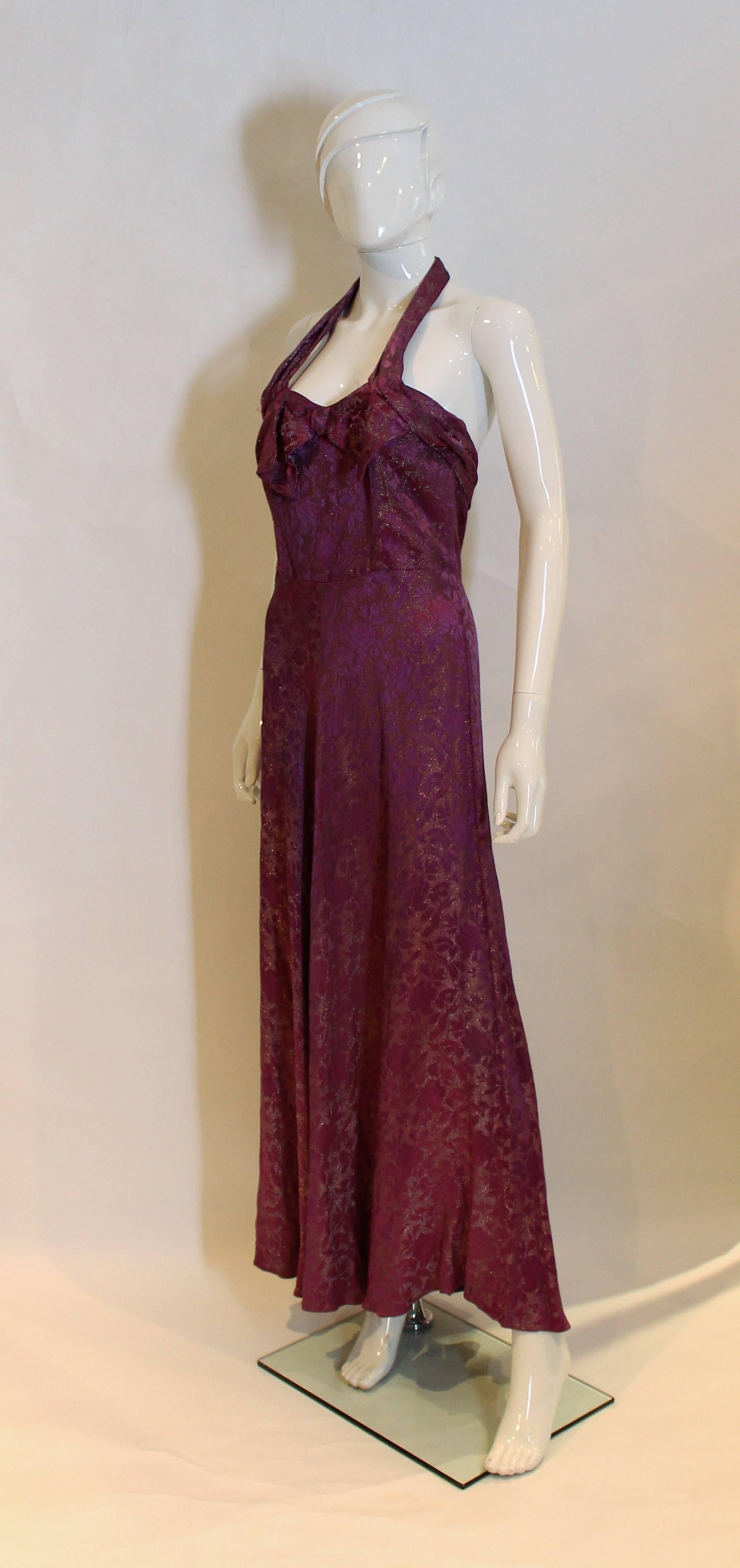 A stunning Lame gown in a pretty purple colour. The dress has a halter neck, fold over detail at the front and back and central back zip.