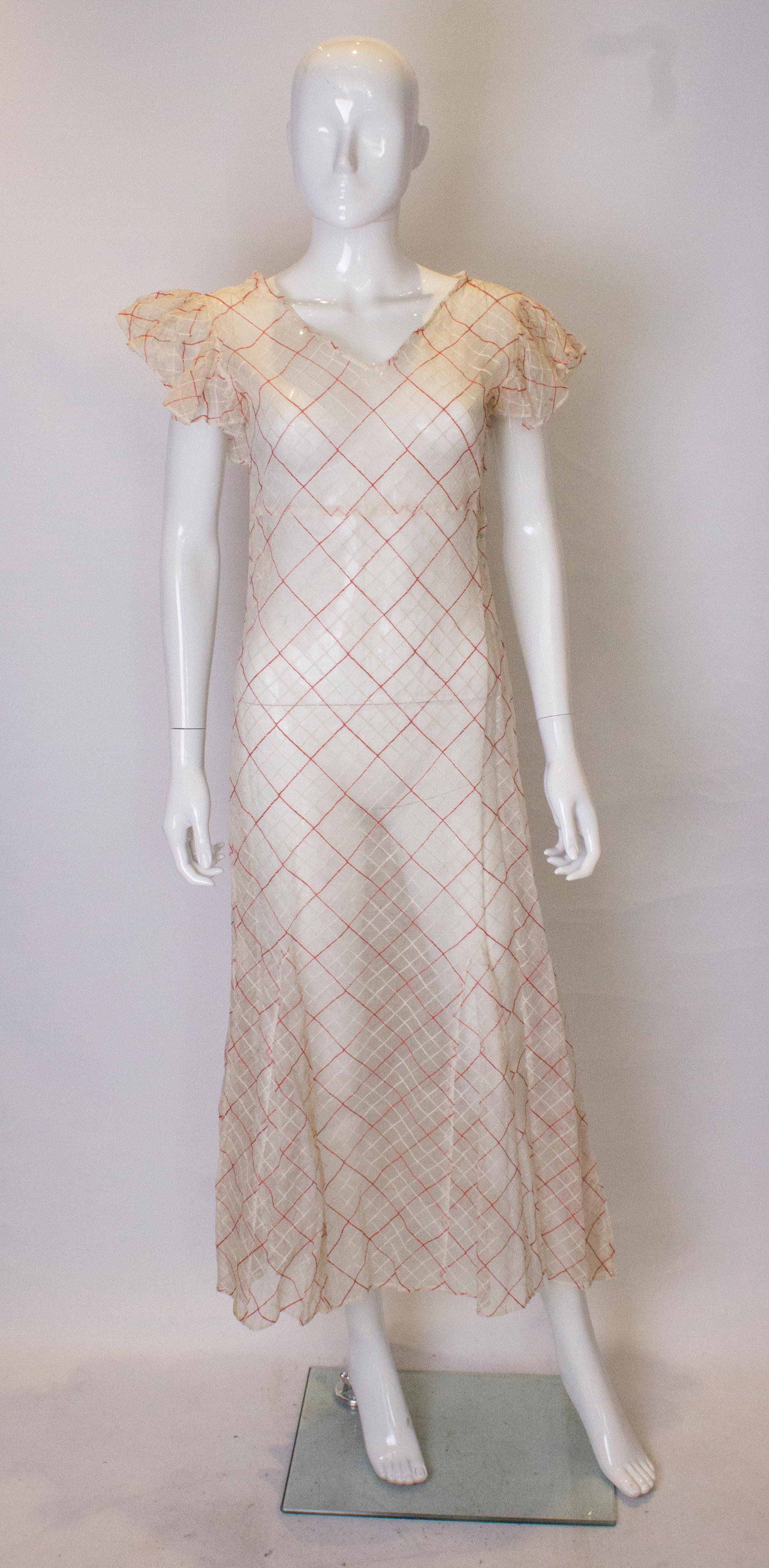 A stunning gown for a Summer party. This 1930s dress is in a red and white voile . It has a v neckline . frills on the arm holes and a side popper opening.