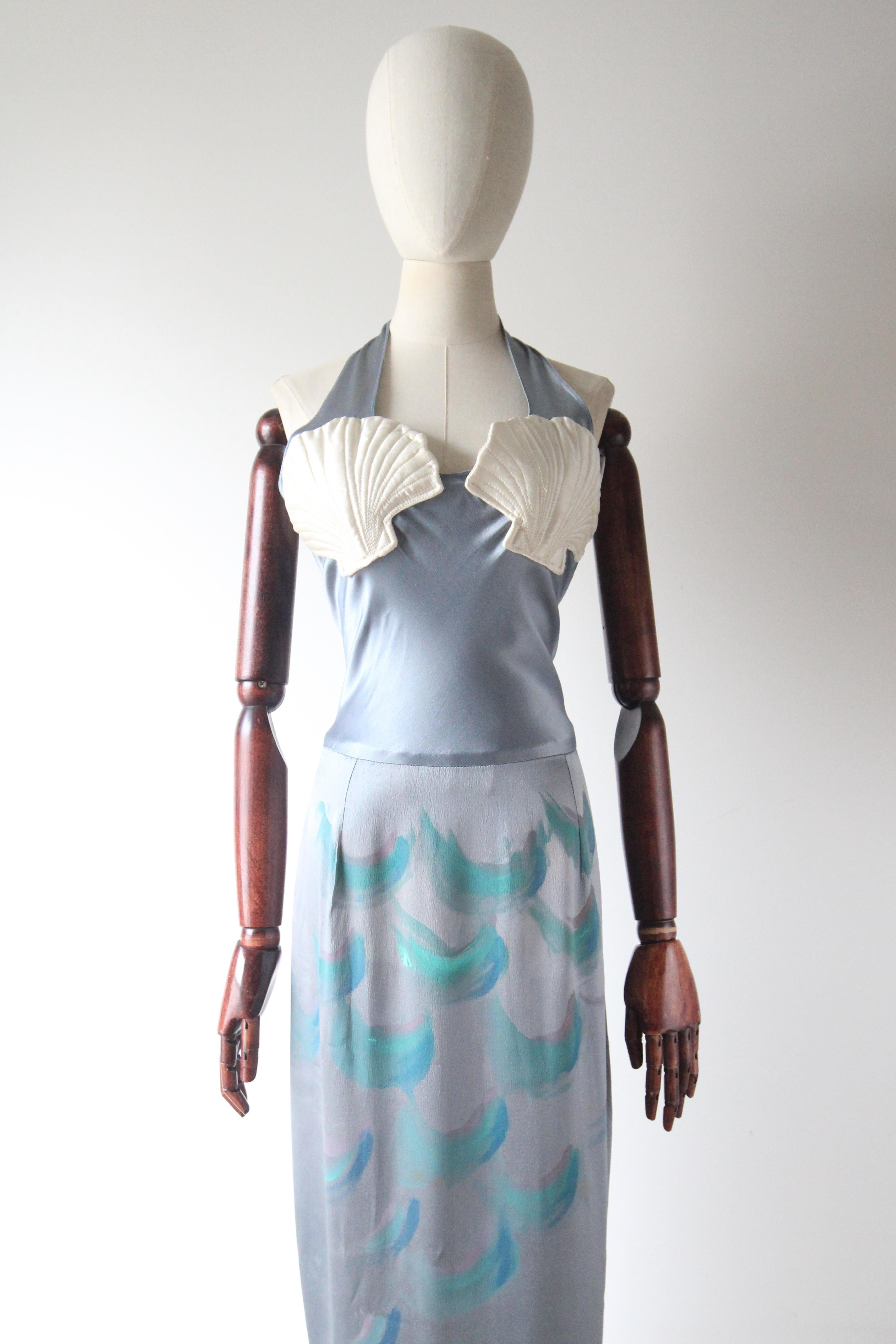 A marvel to behold, this original 1930's vintage dress, rendered in a sumptuous shade of ocean blue silk with painted accented and rayon details, is just the piece to add to your vintage collection. 

The halter neck design of the dress, boasts a