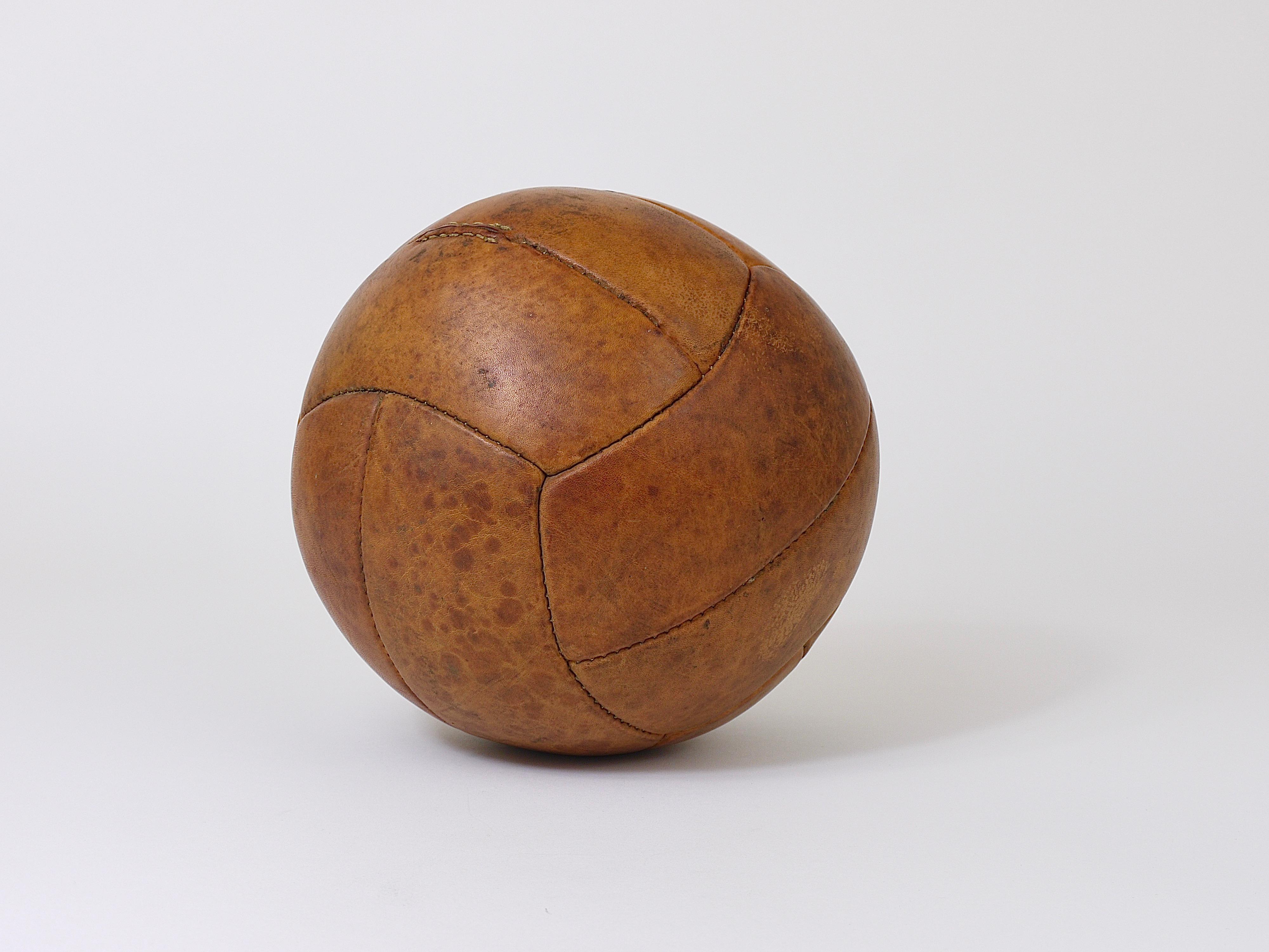 A decorative handcrafted medicine ball from a Czech gym, dated circa 1930s. Made of thick cognac-brown saddle leather in good vintage condition with charming patina. Cleaned and treated with special leather care. Measure: Diameter 9 inches, weight 2
