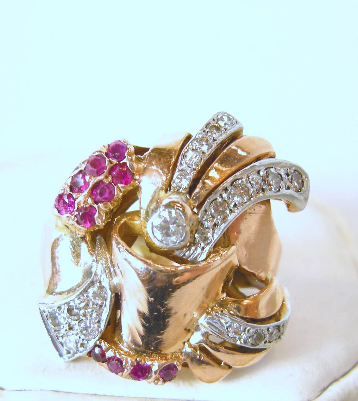 This one of the most unusual retro rings I have seen.  It is 14KT rose gold with approx. 1/2 carat of rubies on the bottom and sides.  It has approx. 1 carat of diamonds dispersed throughout the ring.  It measures 1-1/8” wide x 1” long.  It weighs
