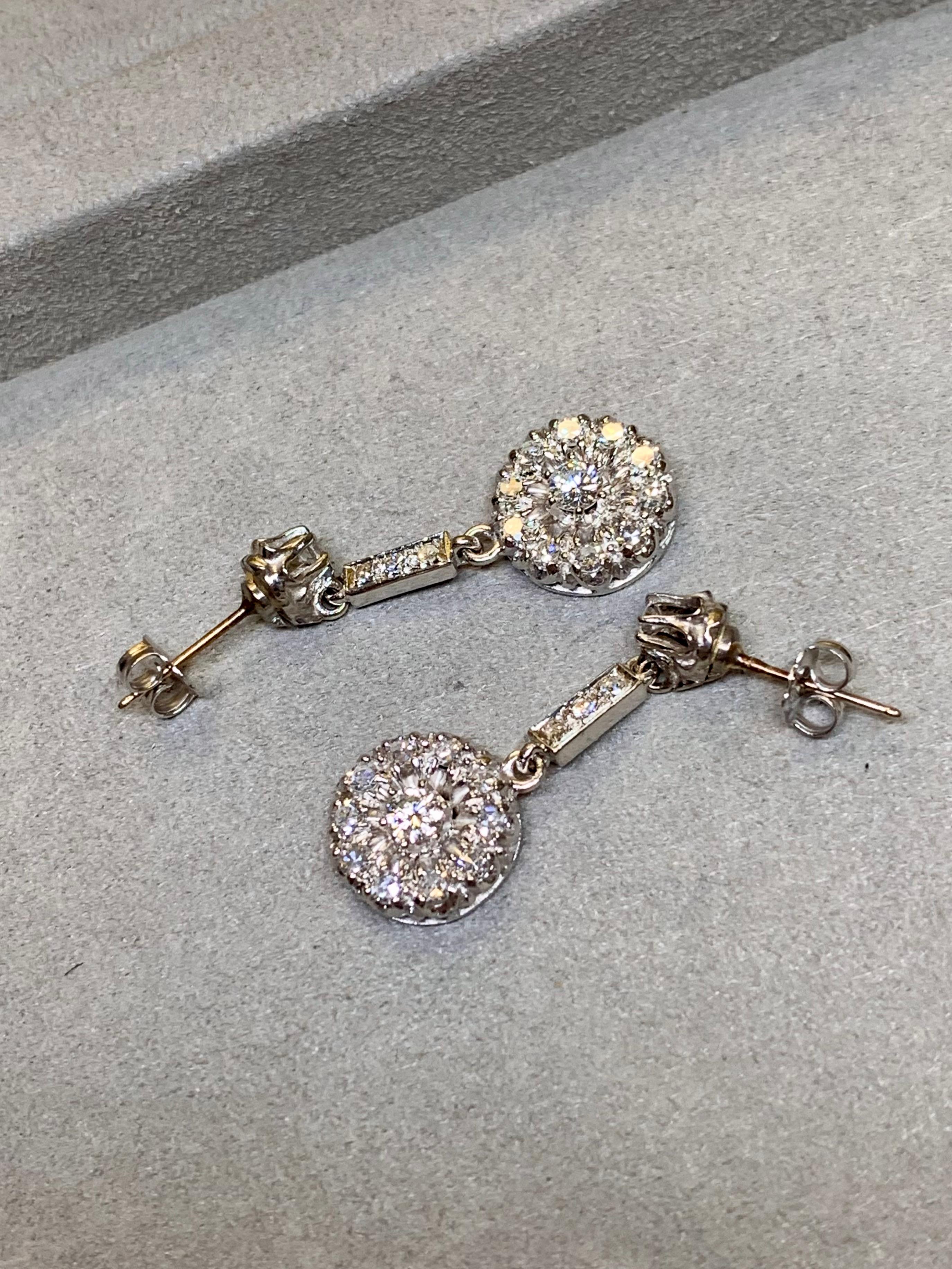 A timeless pair of vintage drop earrings crafted in 14 karat white gold, dating to the 1940s. These elegant earrings are prong set with approximately 1.30 carats of bright, sparkling round diamonds that range F to G in color and VS1 to VS2 in